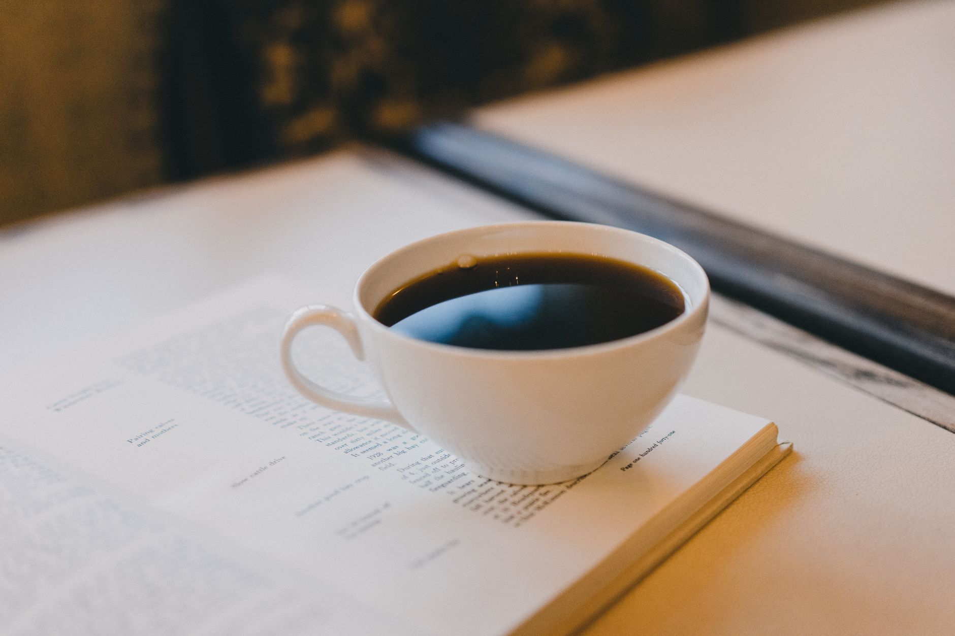 Relax with a warm cup of coffee placed on an open book in a cozy indoor setting.