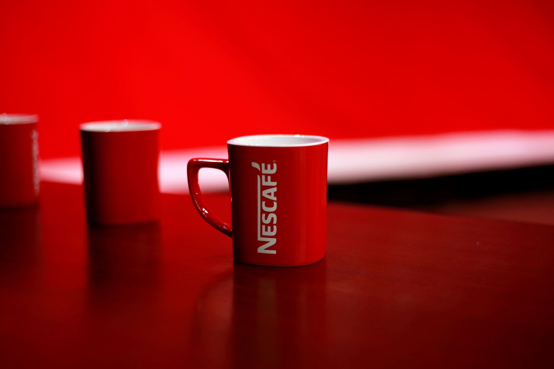Bright red coffee mug featuring bold branding on a clean studio background.