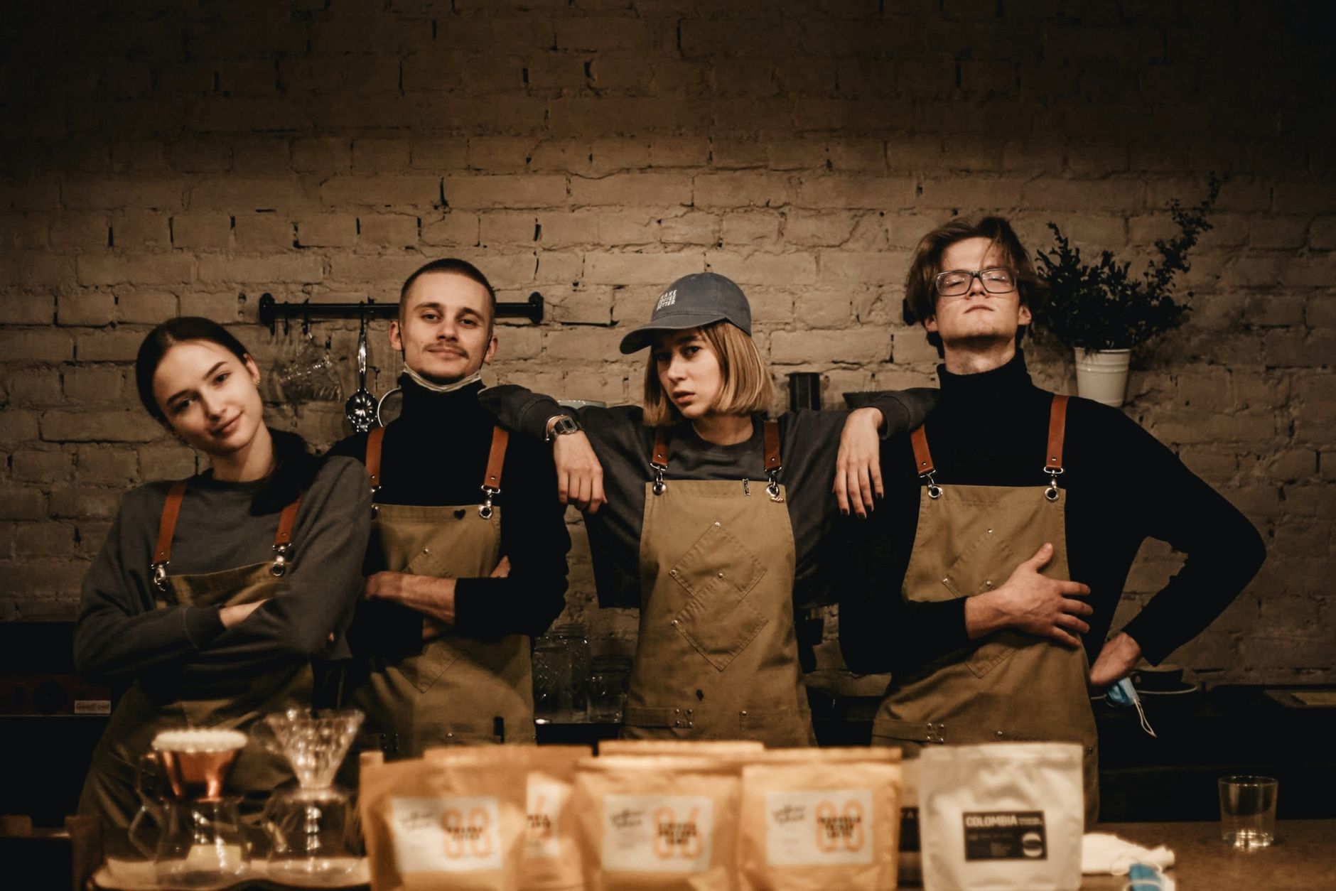 A group of baristas posing confidently in a cozy coffee shop.