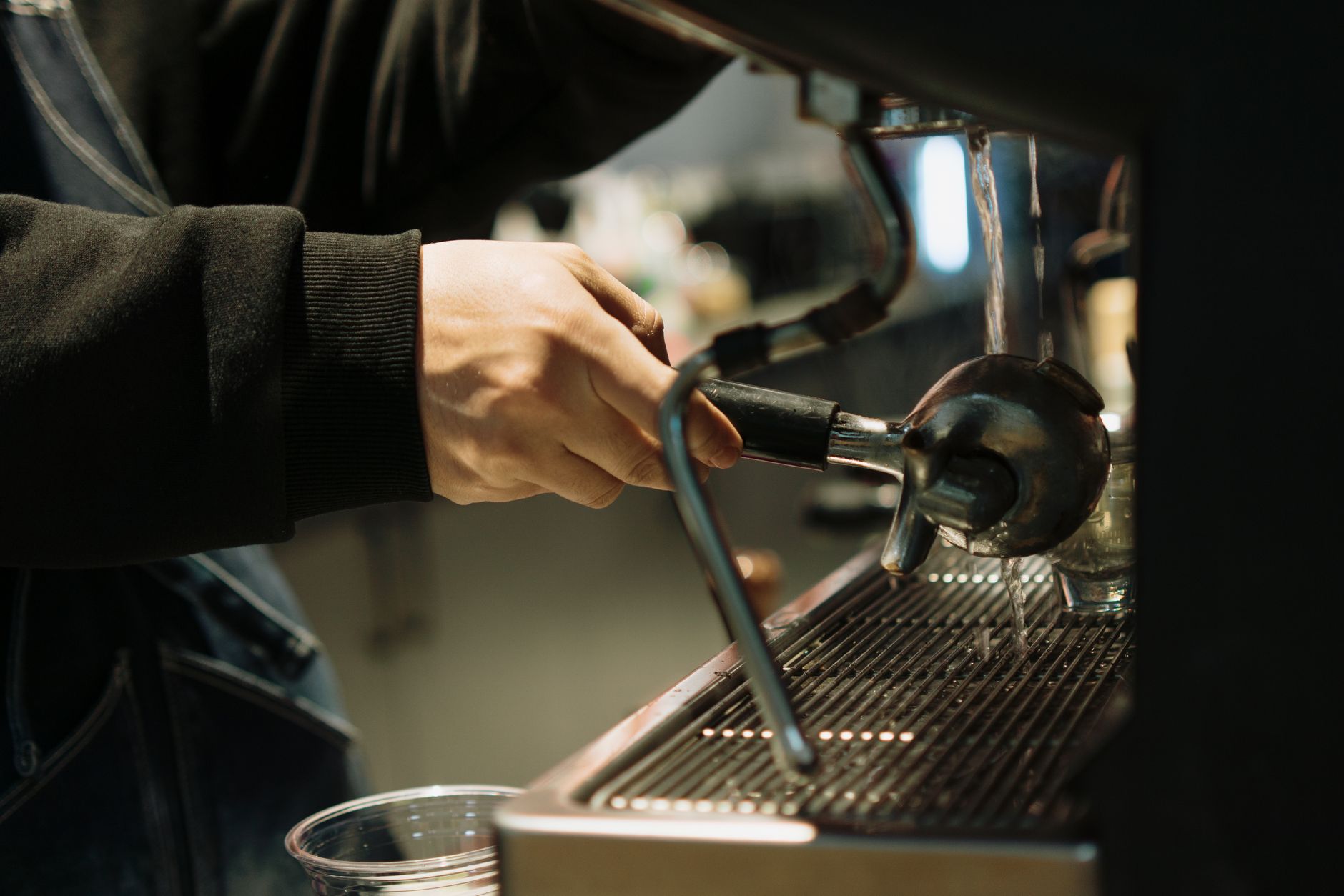A barista pulls an espresso shot in a coffee machine, showcasing precision and skill.