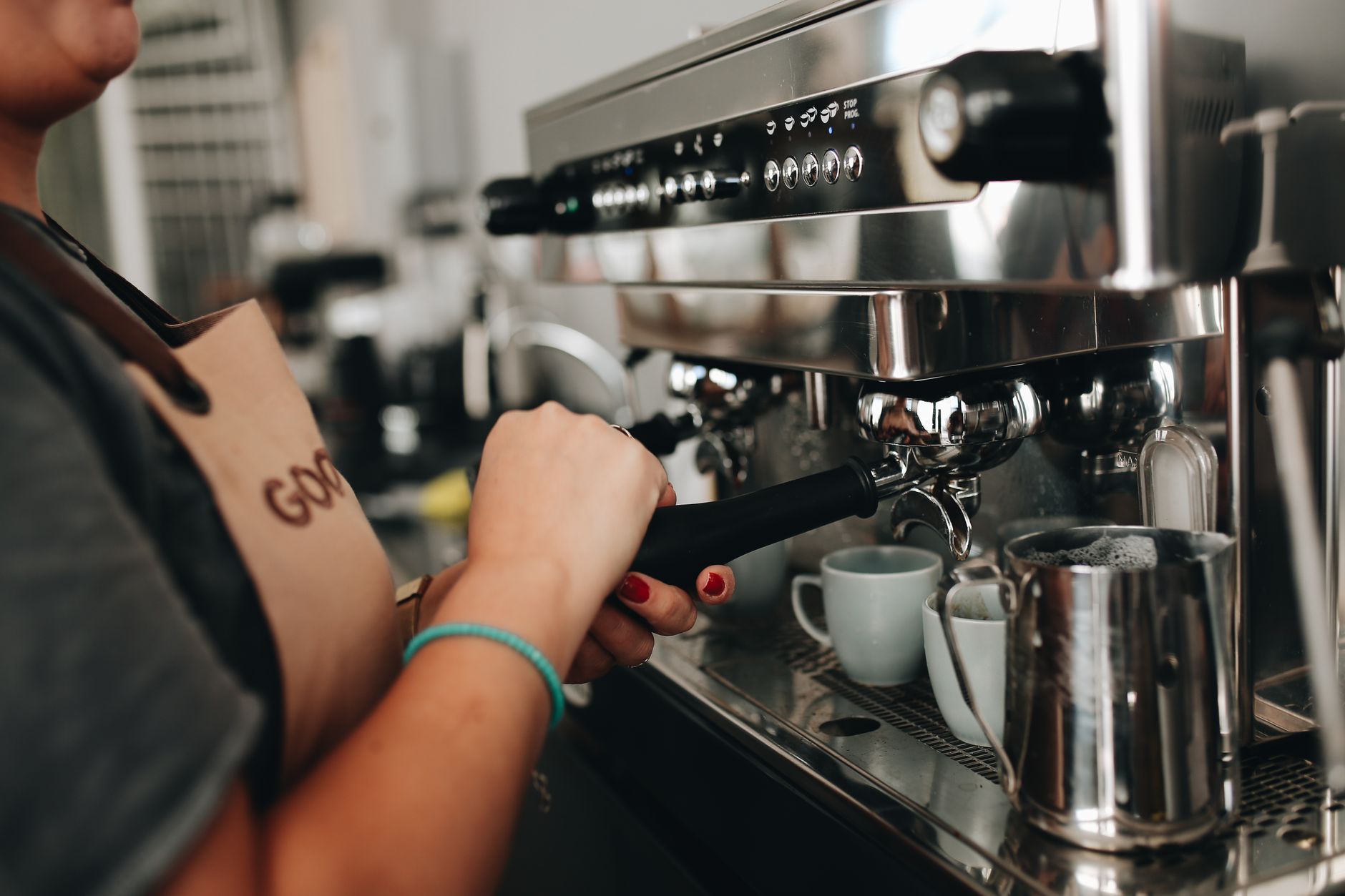 Close-up of a barista using an espresso machine in a cozy café setting.