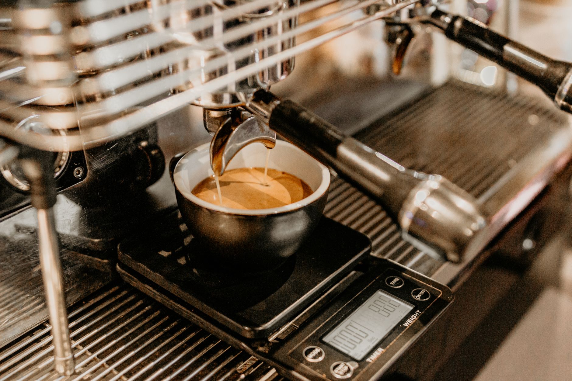 Mug of freshly brewed aromatic coffee placed on cup holder of modern coffee machine in contemporary cafeteria with professional equipment