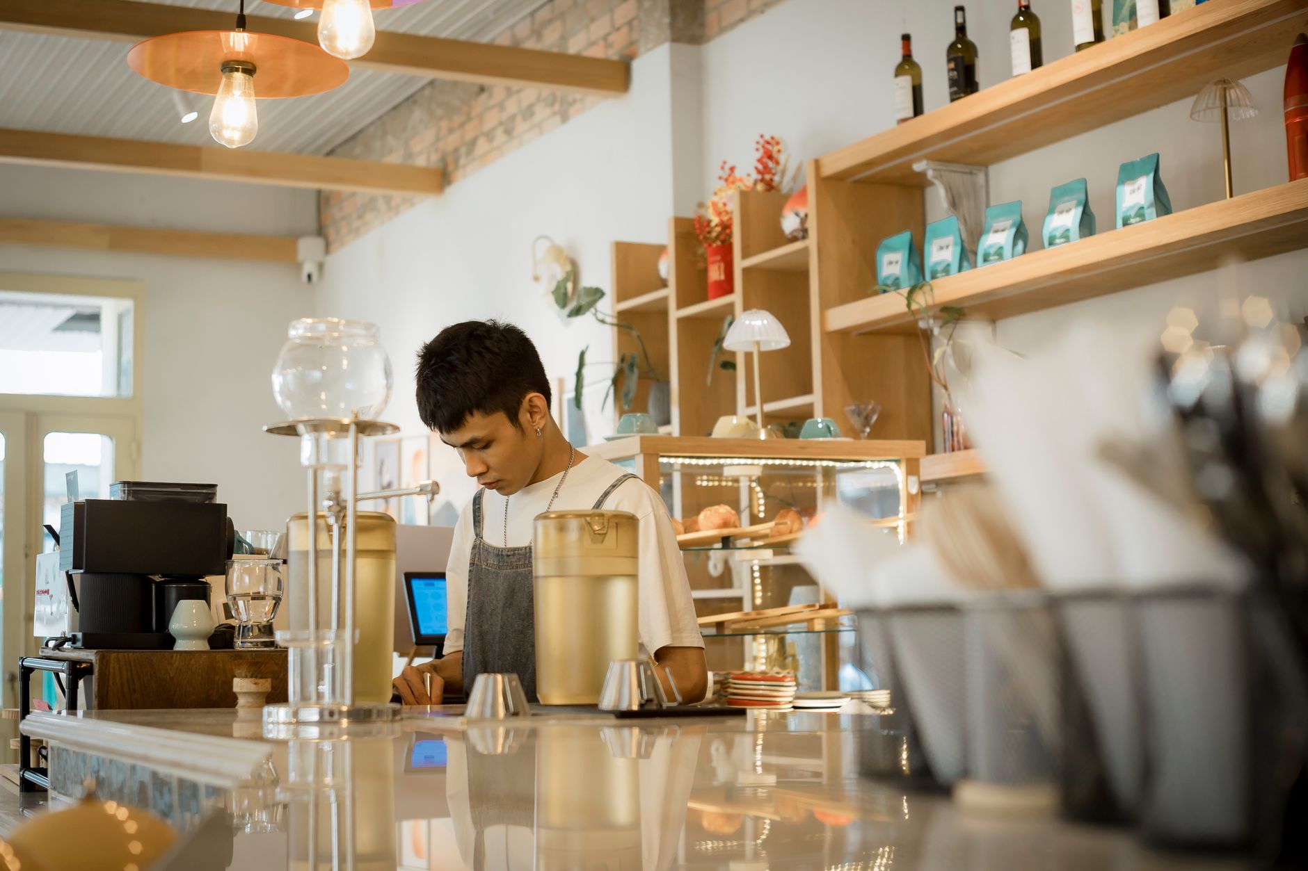 Young barista working in a stylish cafe preparing coffee drinks. Urban lifestyle setting.