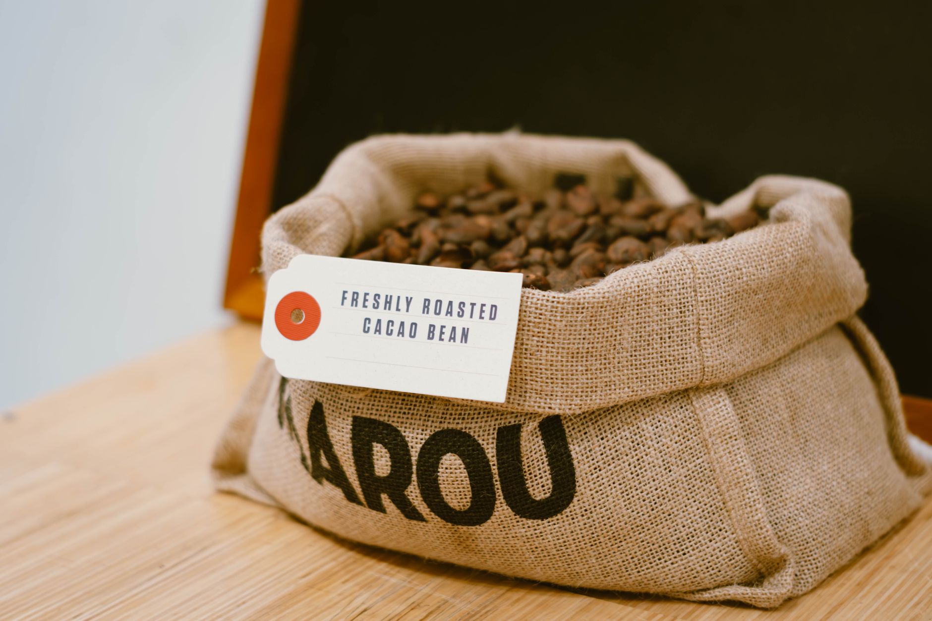 Sack of freshly roasted cacao beans with label 'Freshly Roasted Cacao Bean', ideal for coffee and chocolate themes.