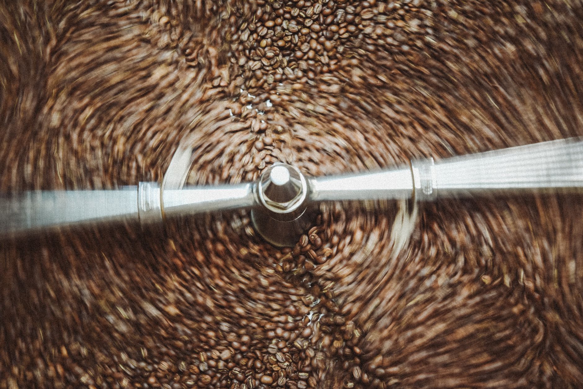 Dynamic close-up shot of coffee beans swirling in a roasting machine, showcasing the roasting process.