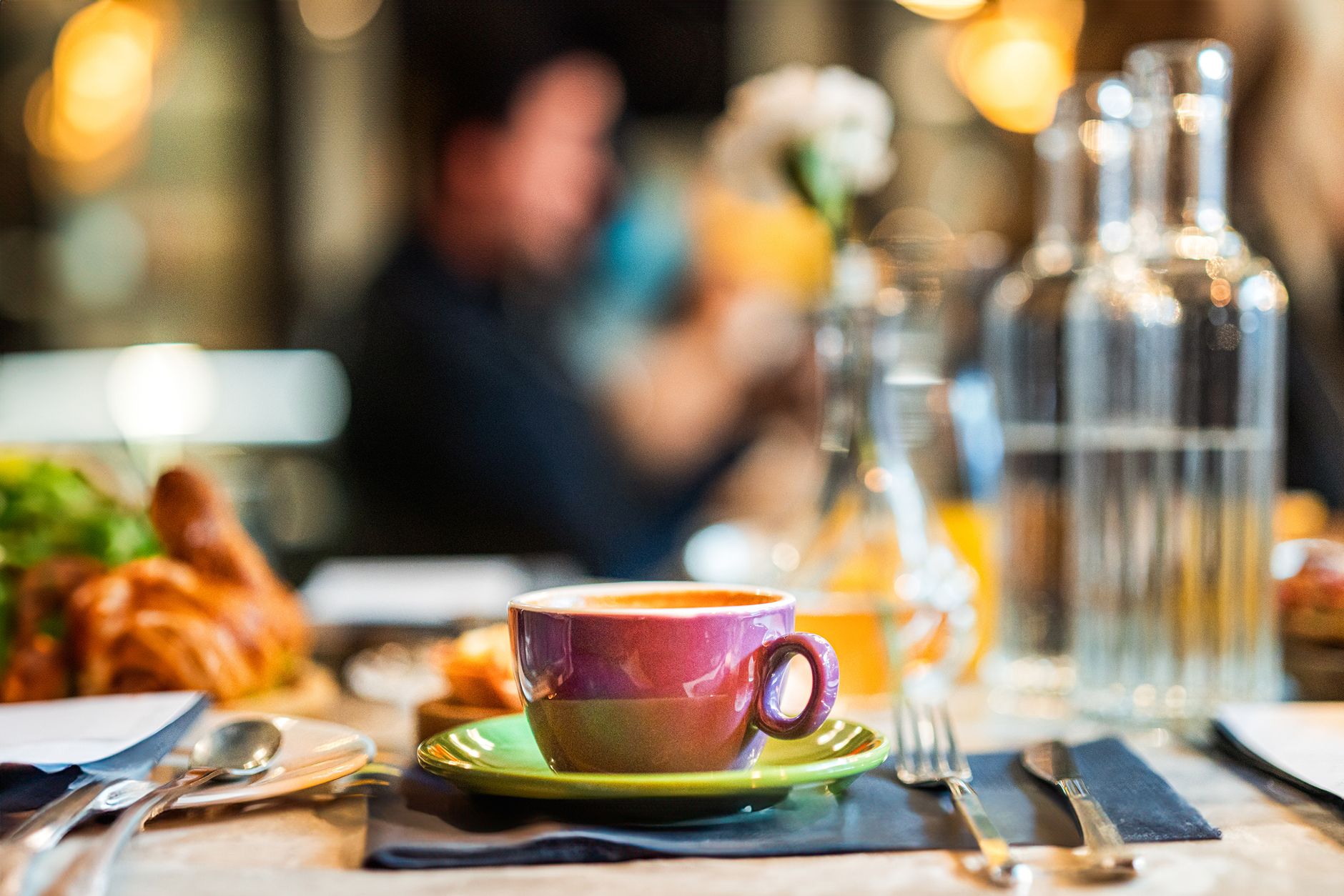 A vibrant cafe setting featuring a colorful coffee cup and breakfast items on a table.