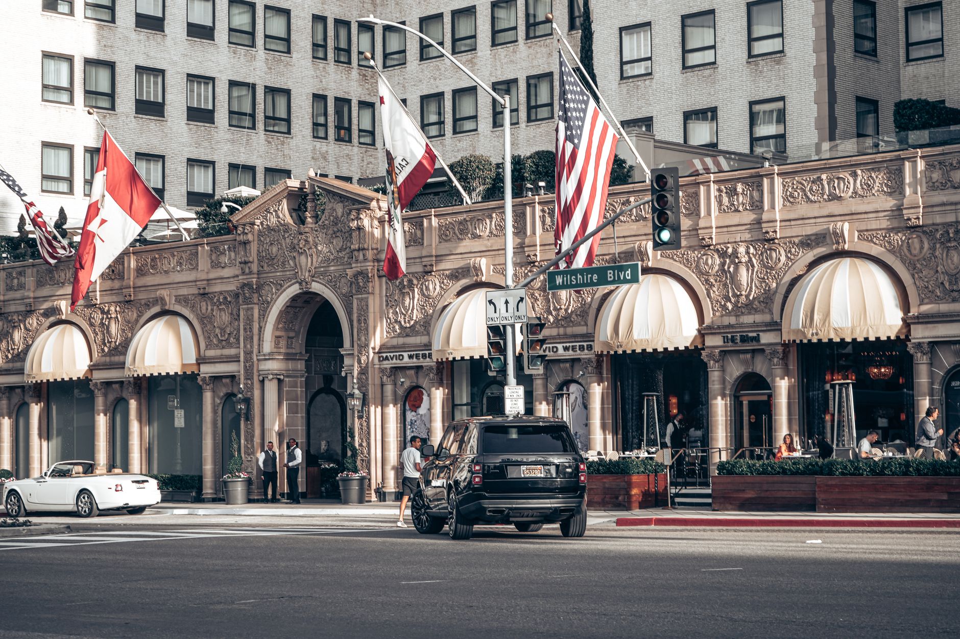 Elegant Beverly Hills street scene featuring a famous hotel with classic architecture and a Range Rover.