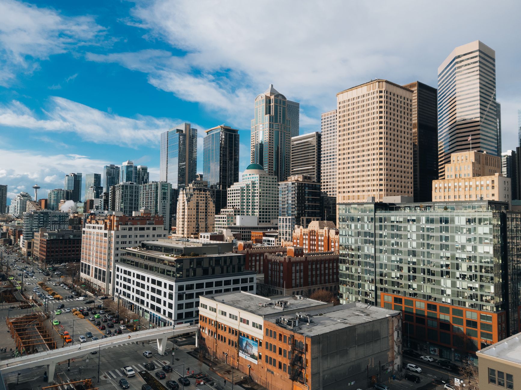 Aerial view of downtown Seattle's skyline featuring iconic skyscrapers under a bright blue sky.