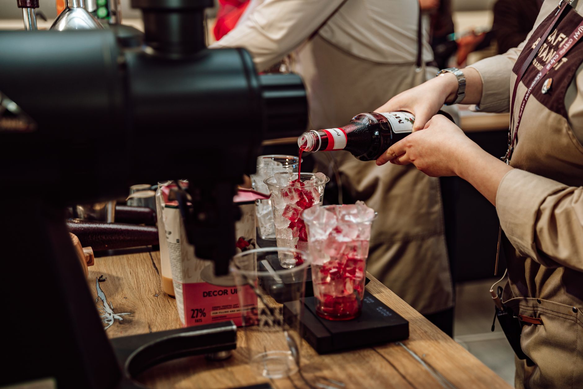 Barista preparing iced beverages with syrup in a Baku café. Captured indoors.