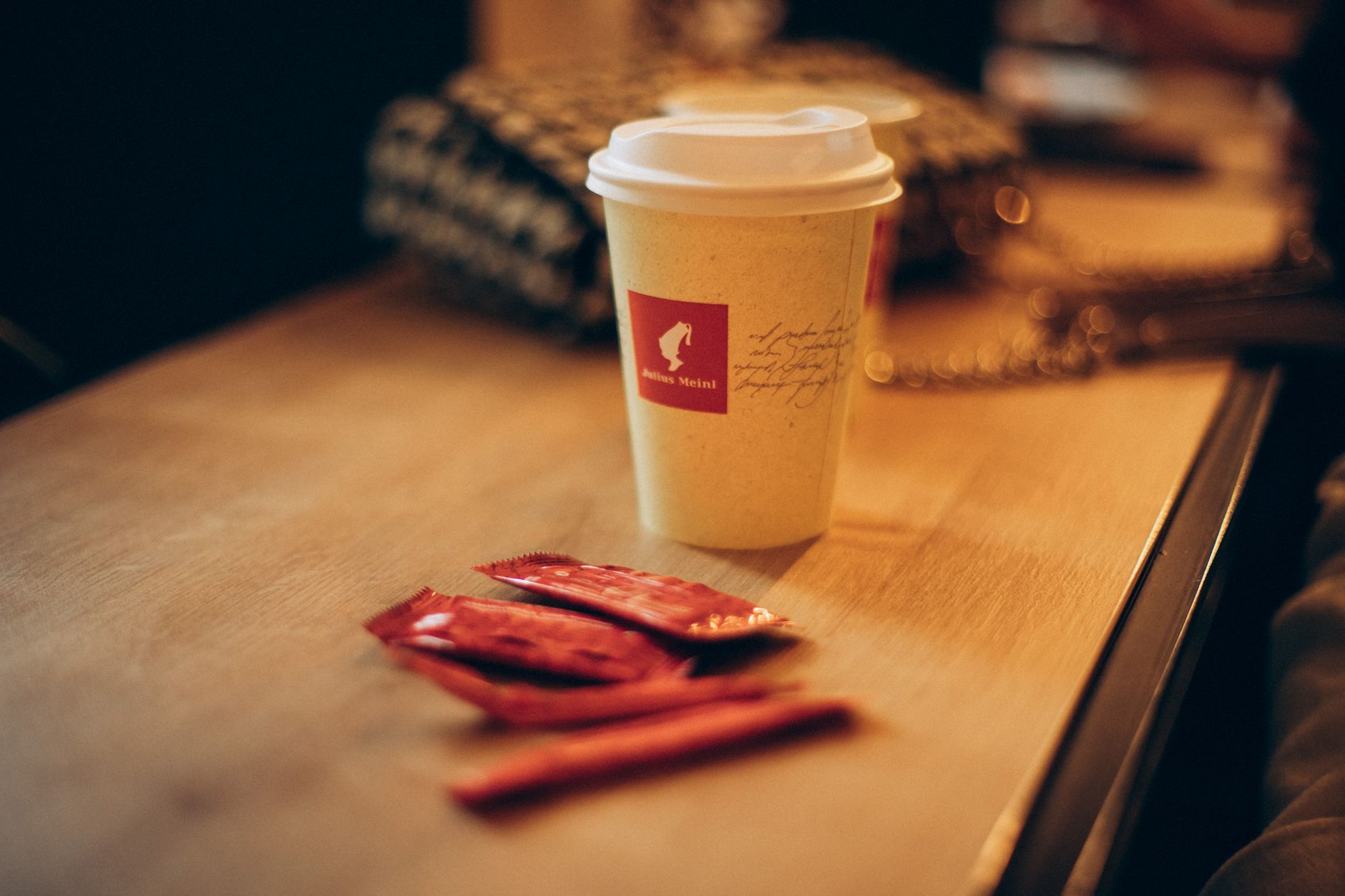 Cozy coffee cup on a rustic table with sugar packets, creating a warm indoor atmosphere.