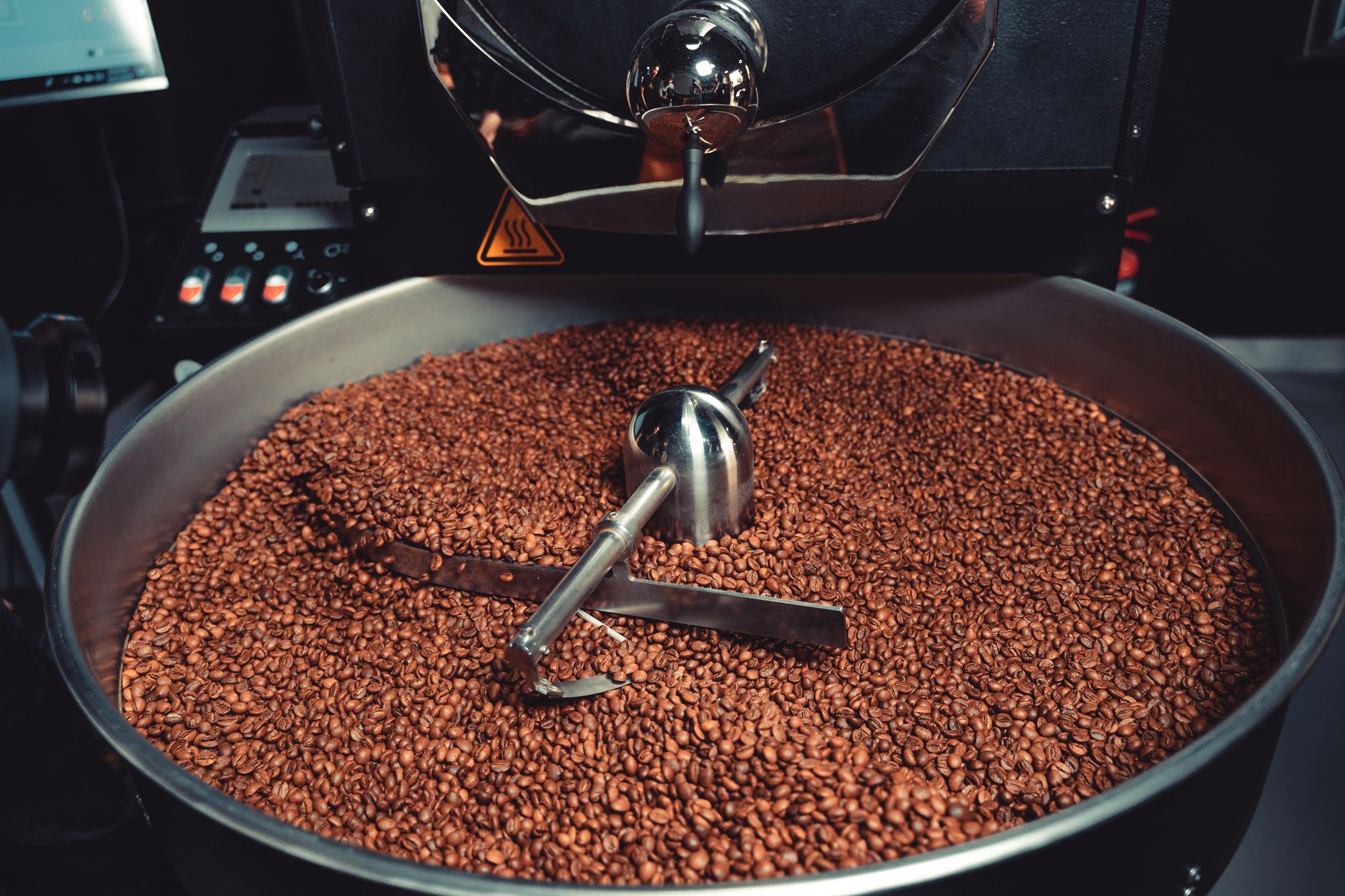A detailed view of freshly roasted coffee beans inside an industrial roaster, showcasing machinery and process.