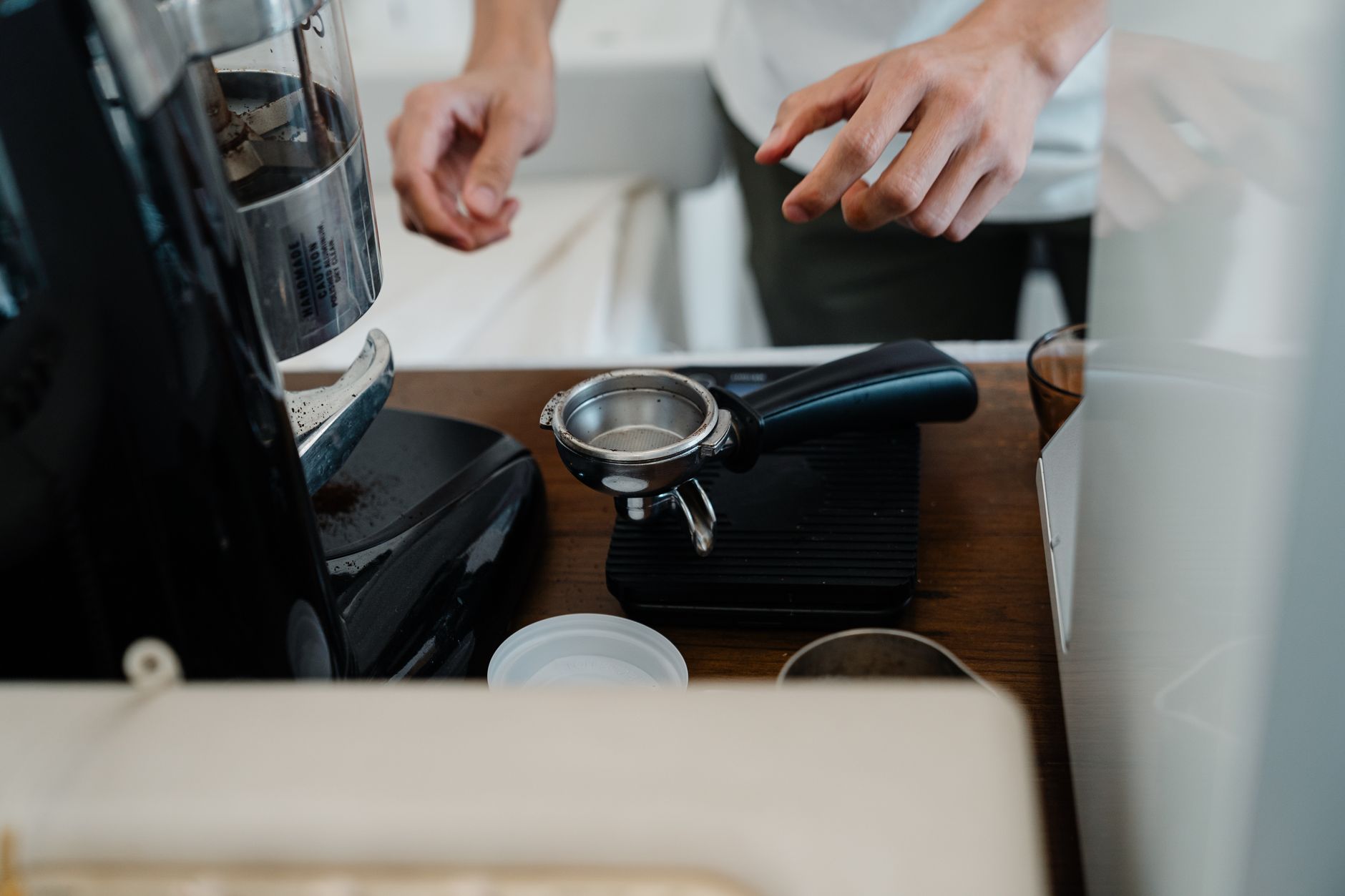 Crop unrecognizable barista in casual clothes making delicious coffee by using portafilter and professional coffee machine while working in contemporary cafeteria