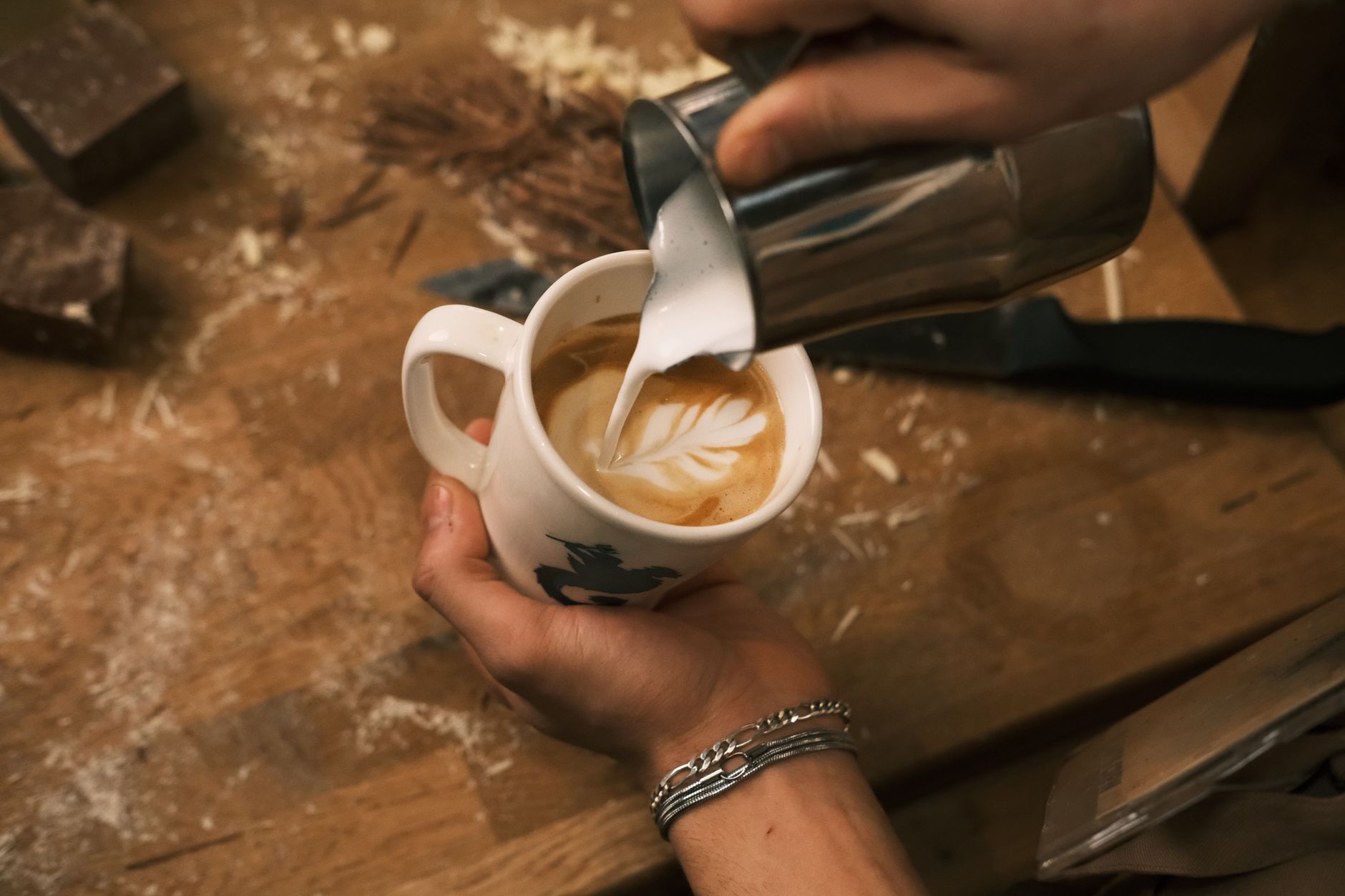Close-up of barista hands pouring milk art in coffee cup in a cozy Konya café.