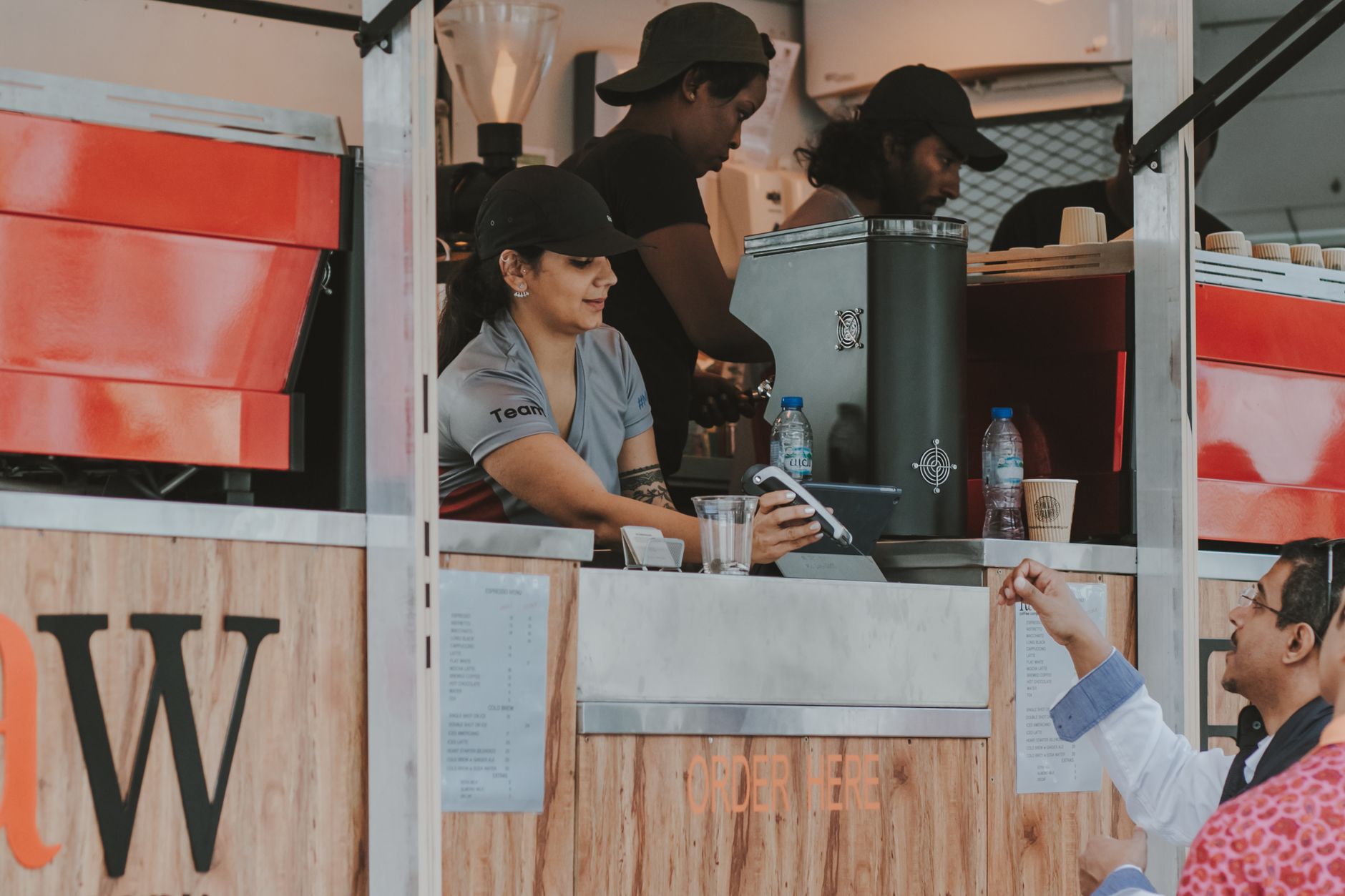 Market scene with diverse individuals at a food stall making a transaction.