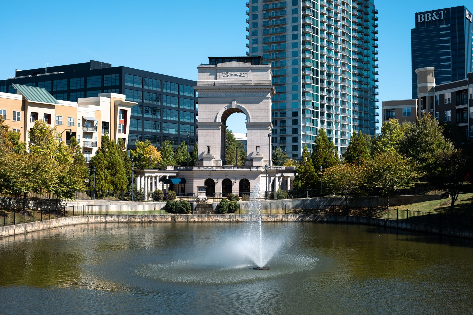 A scenic view of the Millennium Gate with reflections in a fountain, surrounded by Atlanta's cityscape.