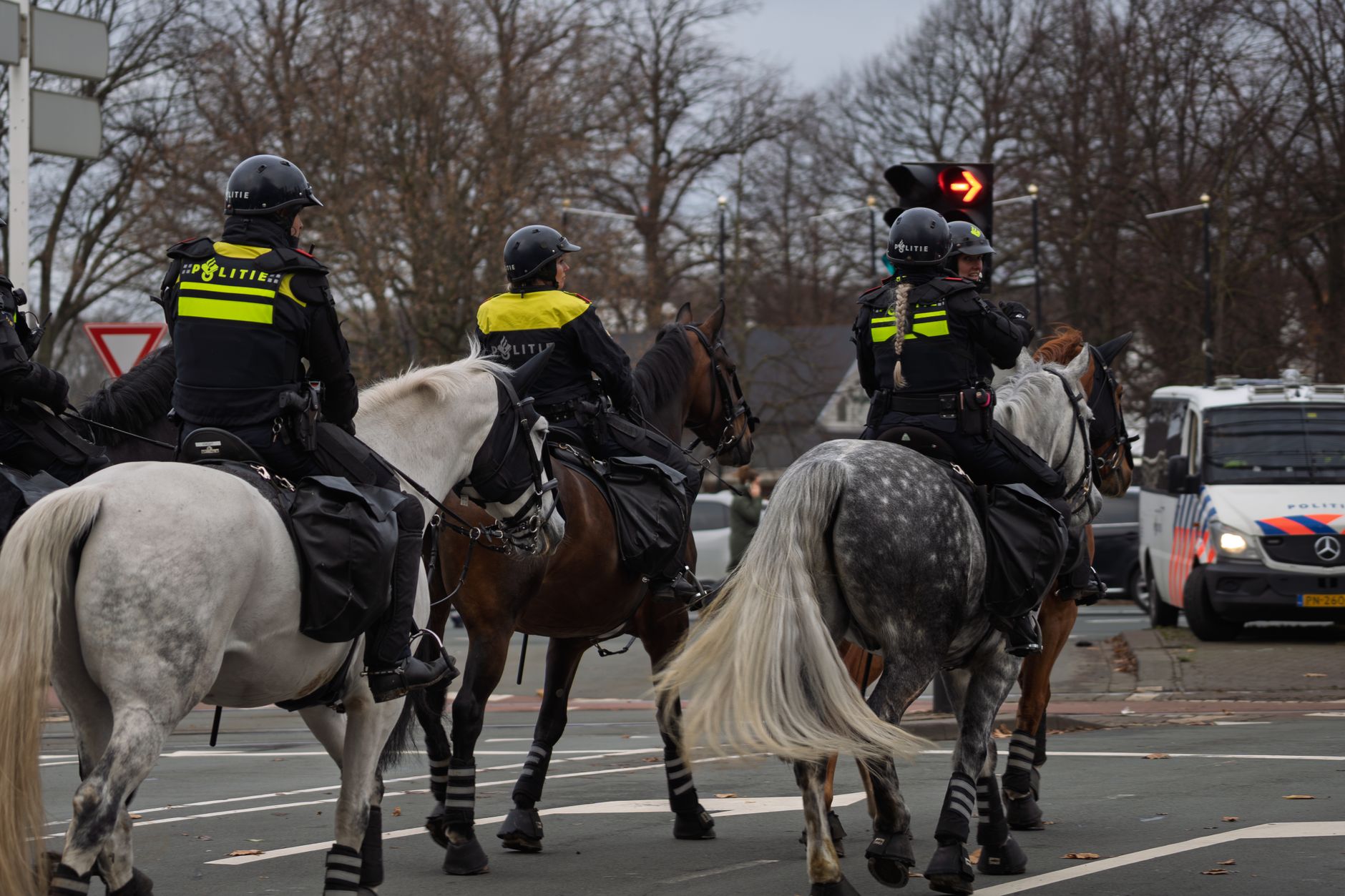 Mounted Dutch police on patrol in a city intersection during winter.