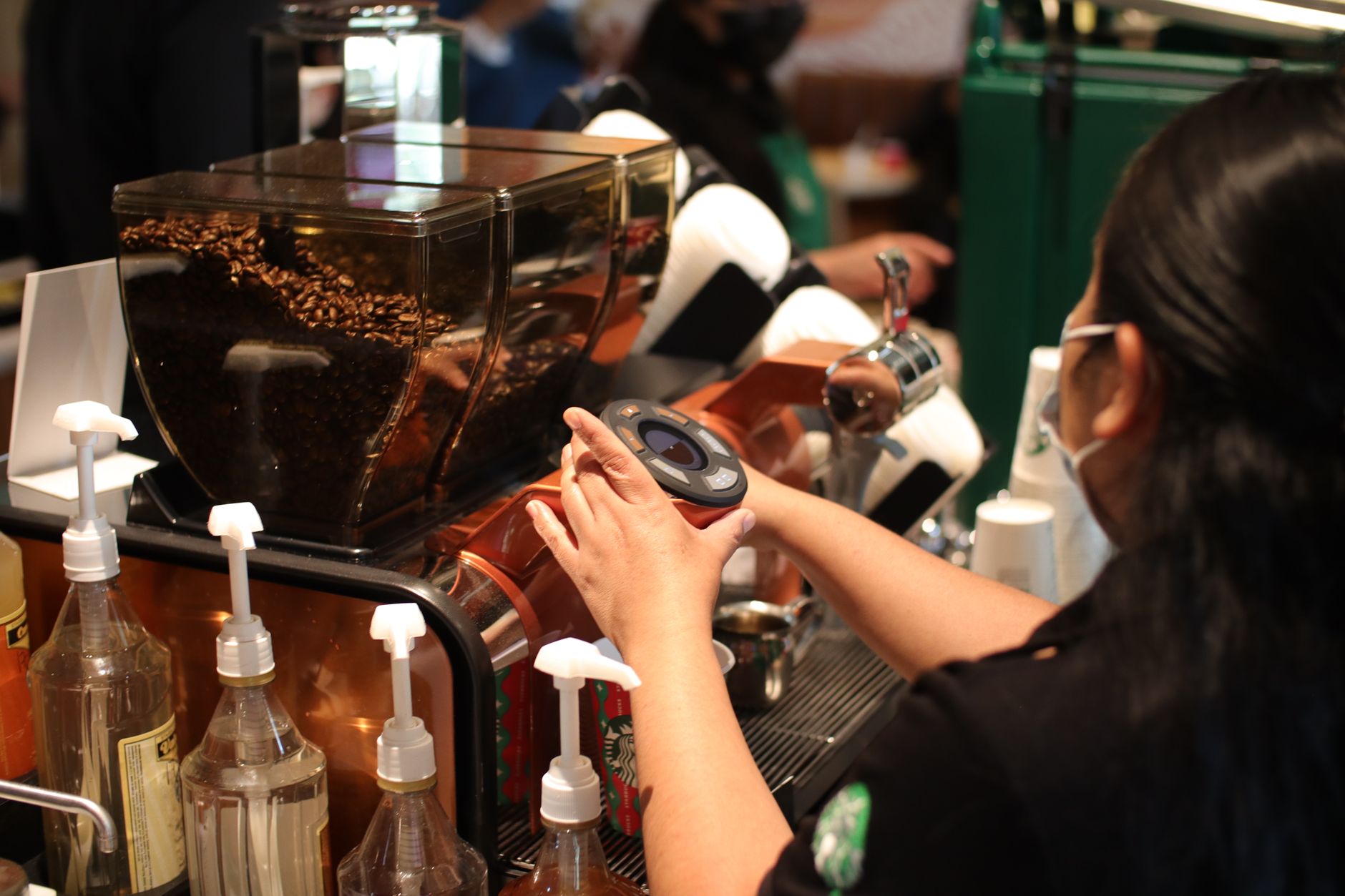 Barista expertly prepares a coffee shot in a bustling café environment.