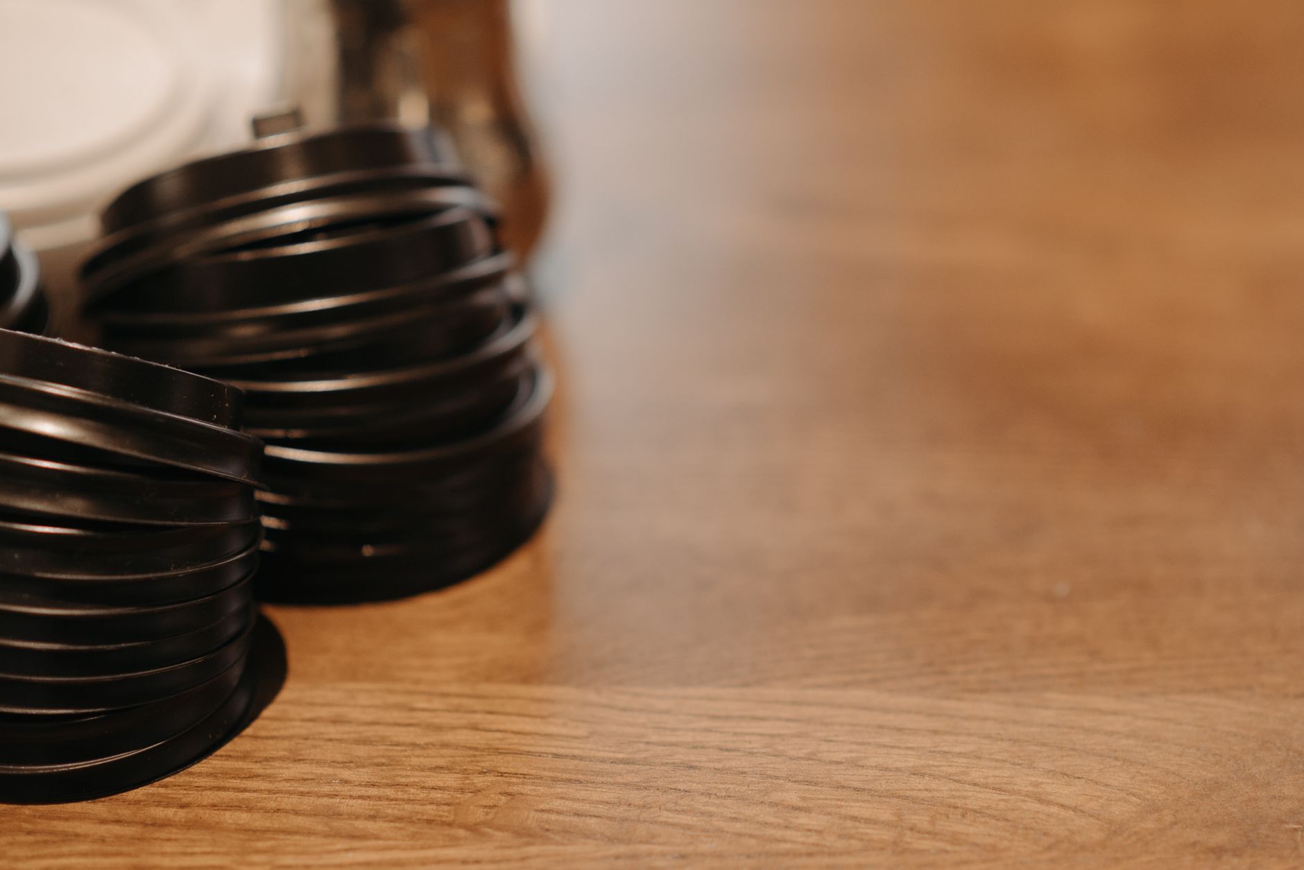 Close-up of black coffee cup lids stacked on a wooden surface, ideal for cafes.