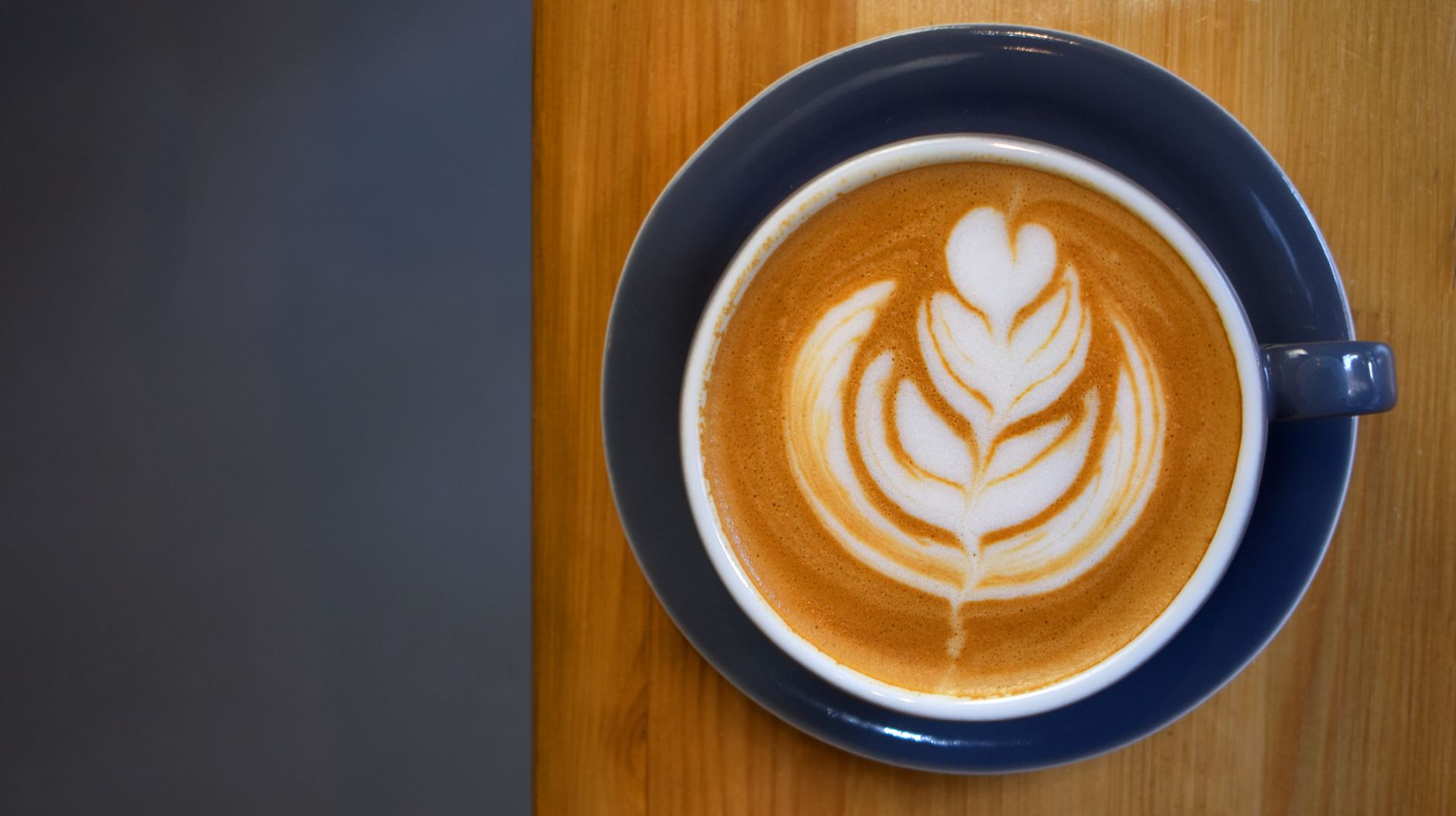 Close-up of a latte with artistic foam design on a wooden table.