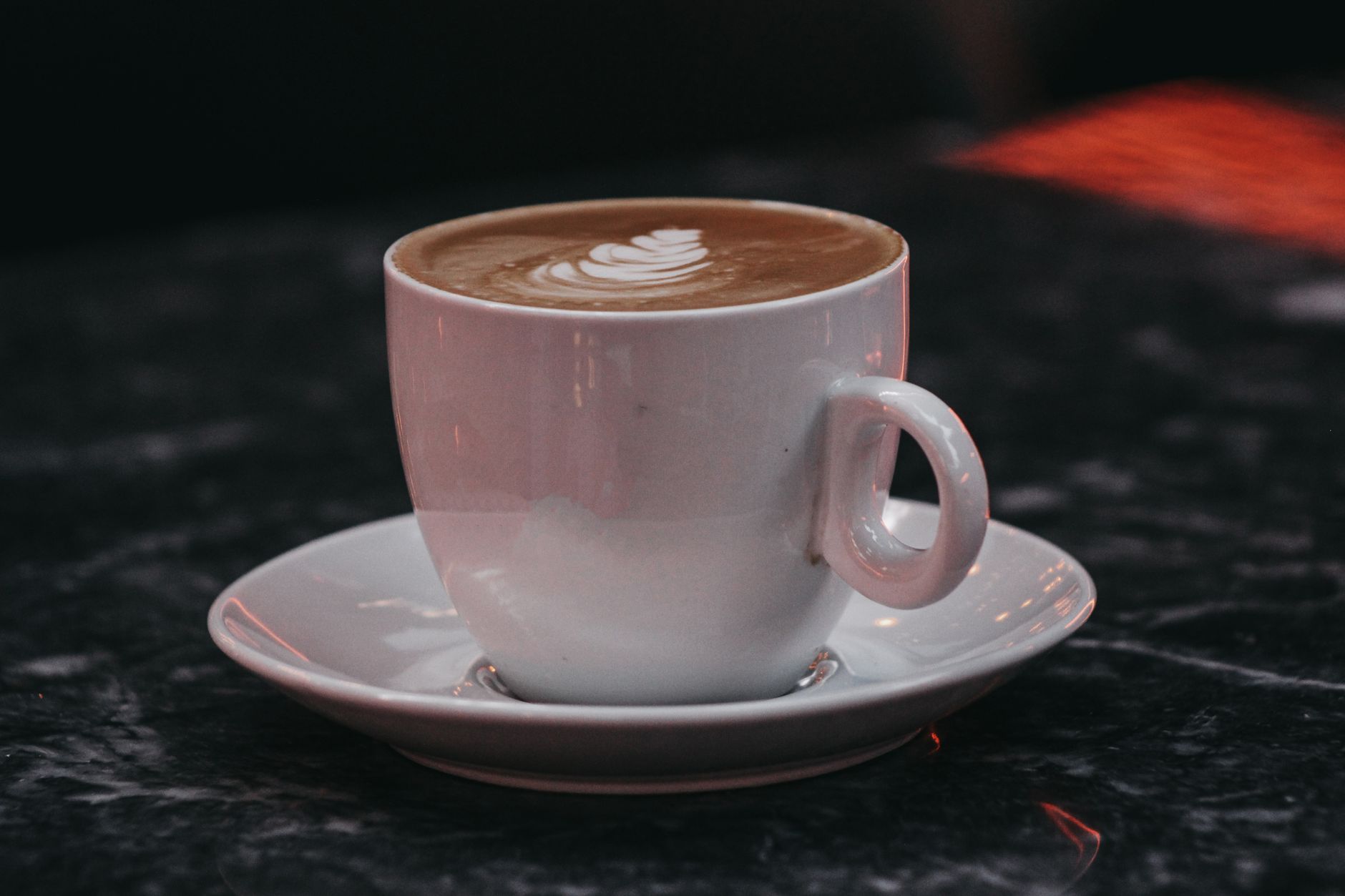 Close-up of a beautifully crafted latte with intricate foam art on a saucer, perfect for coffee enthusiasts.