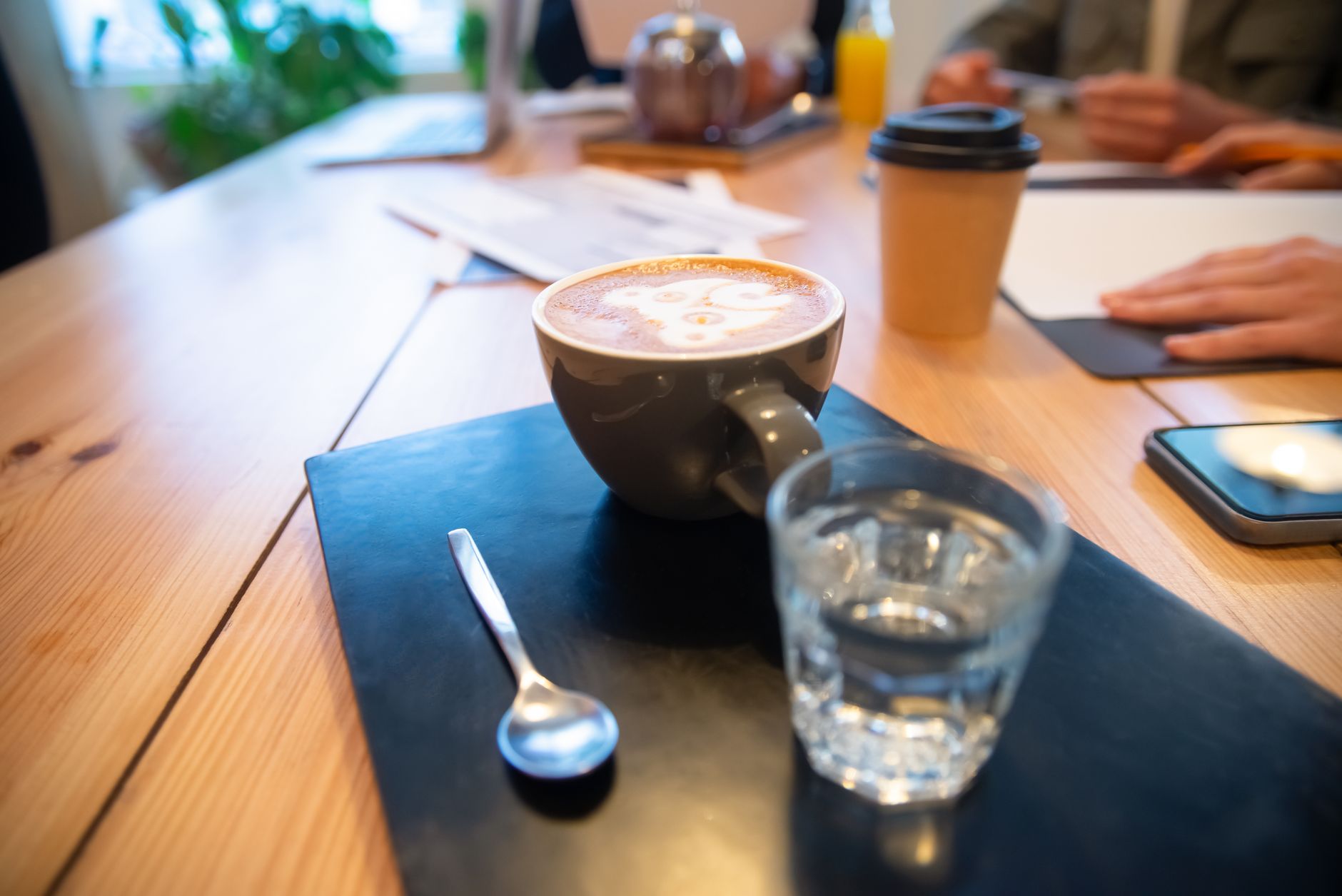 Warm coffee and glass of water on a wooden table at a cozy cafe. Perfect breaktime setting.