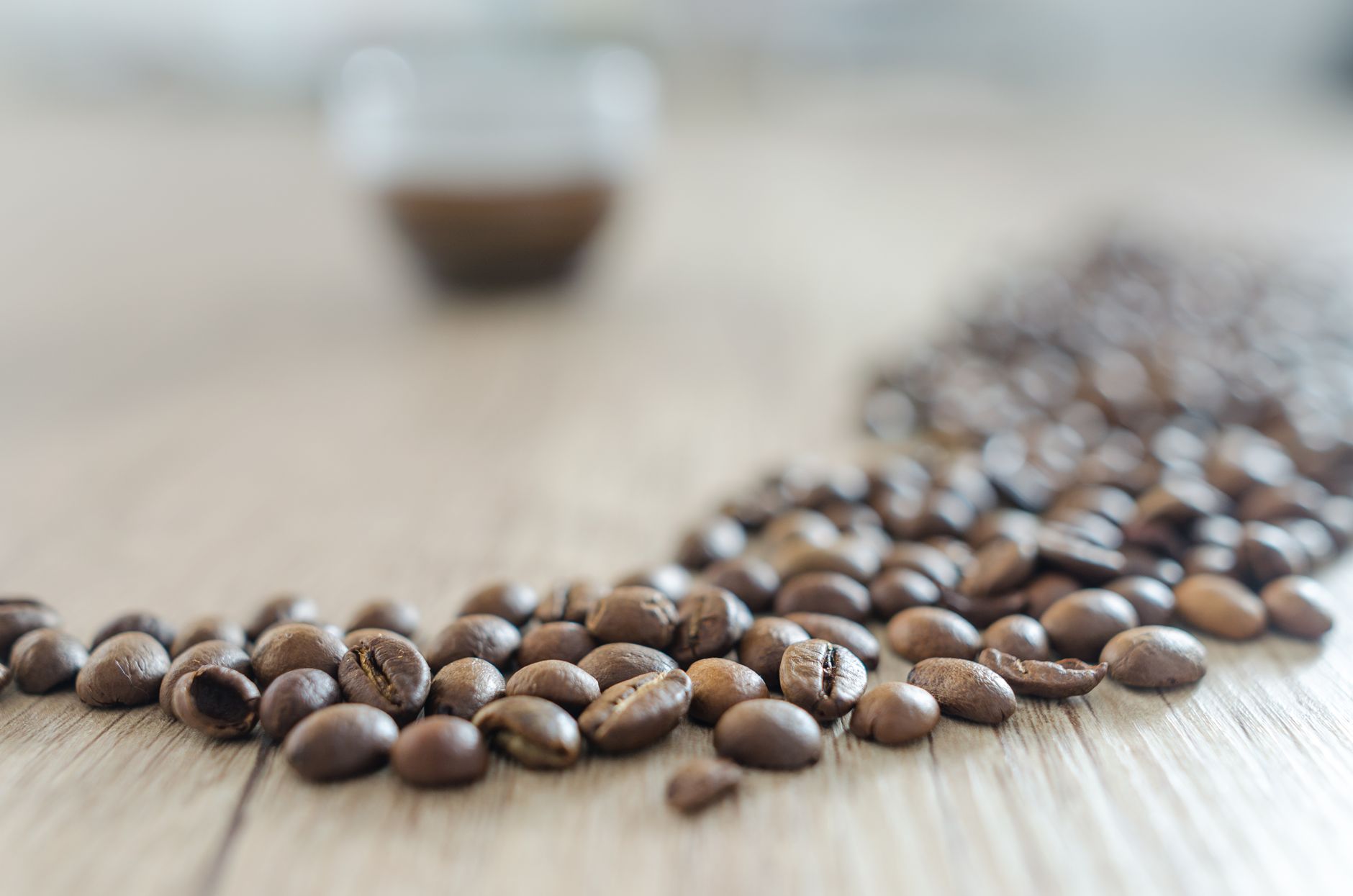 Macro shot of roasted coffee beans scattered on wooden table, focus on foreground.