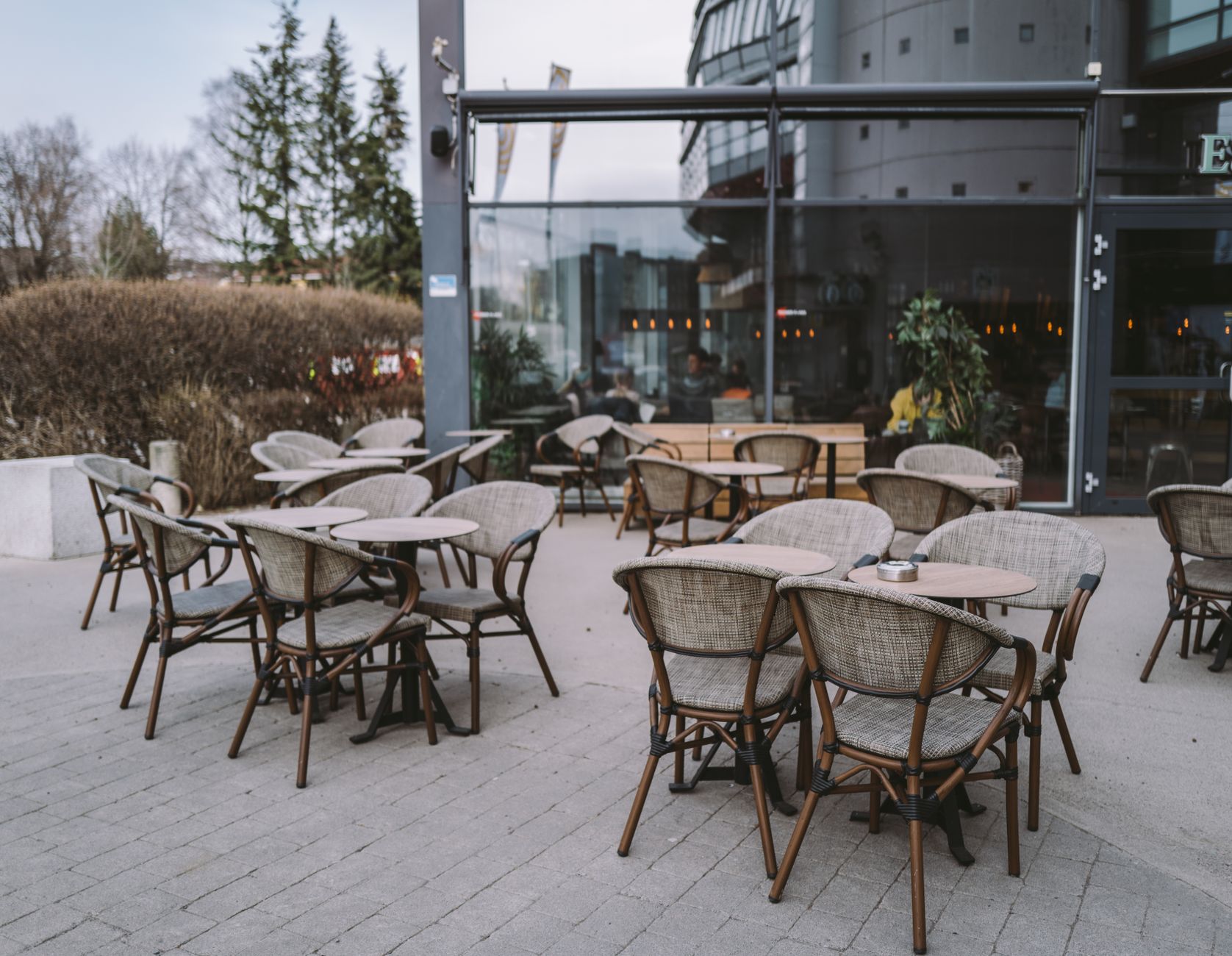 A cozy outdoor café setting with wicker chairs and tables on a paved area, ideal for dining.