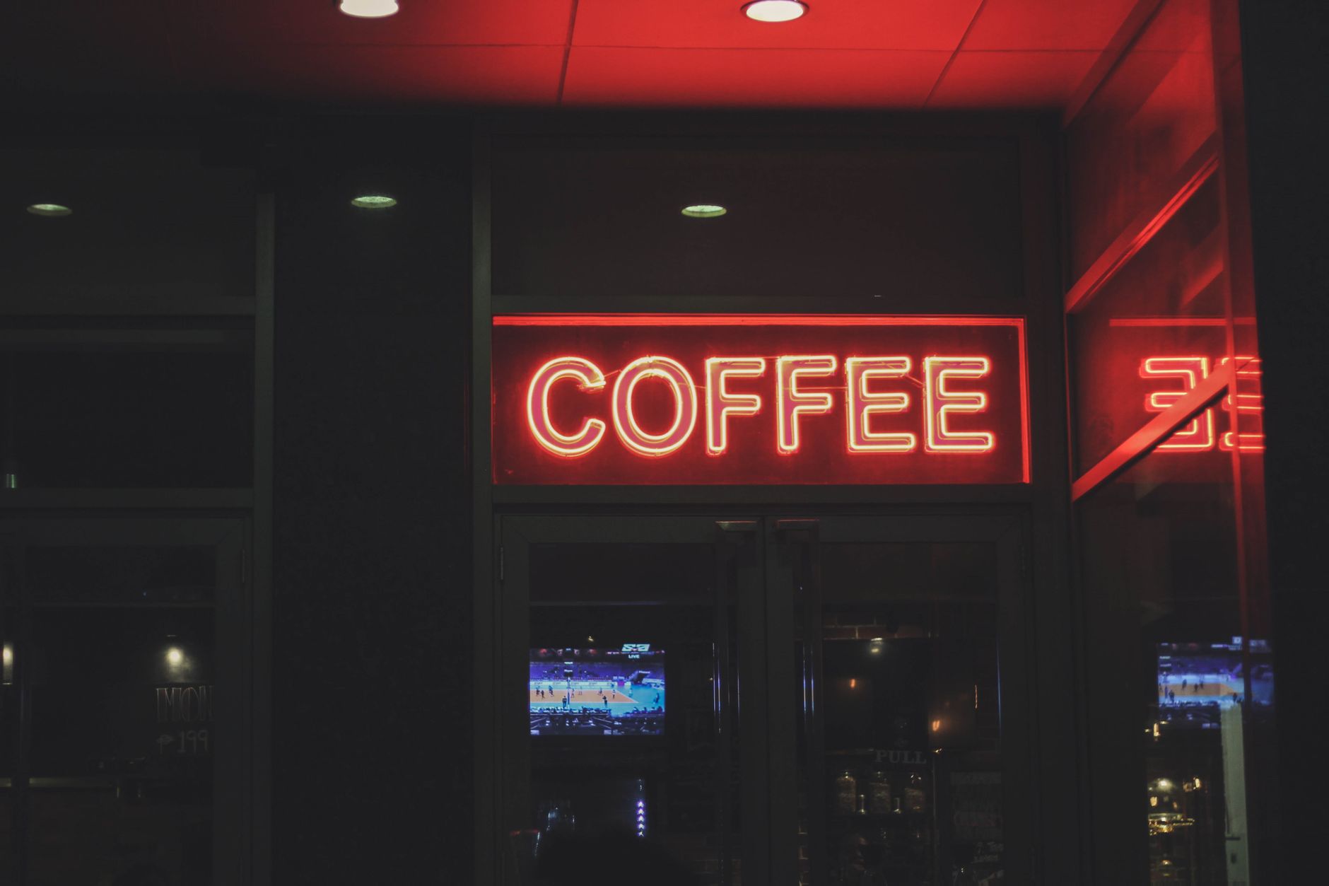 A vibrant neon coffee sign illuminating a modern cafe environment at night.