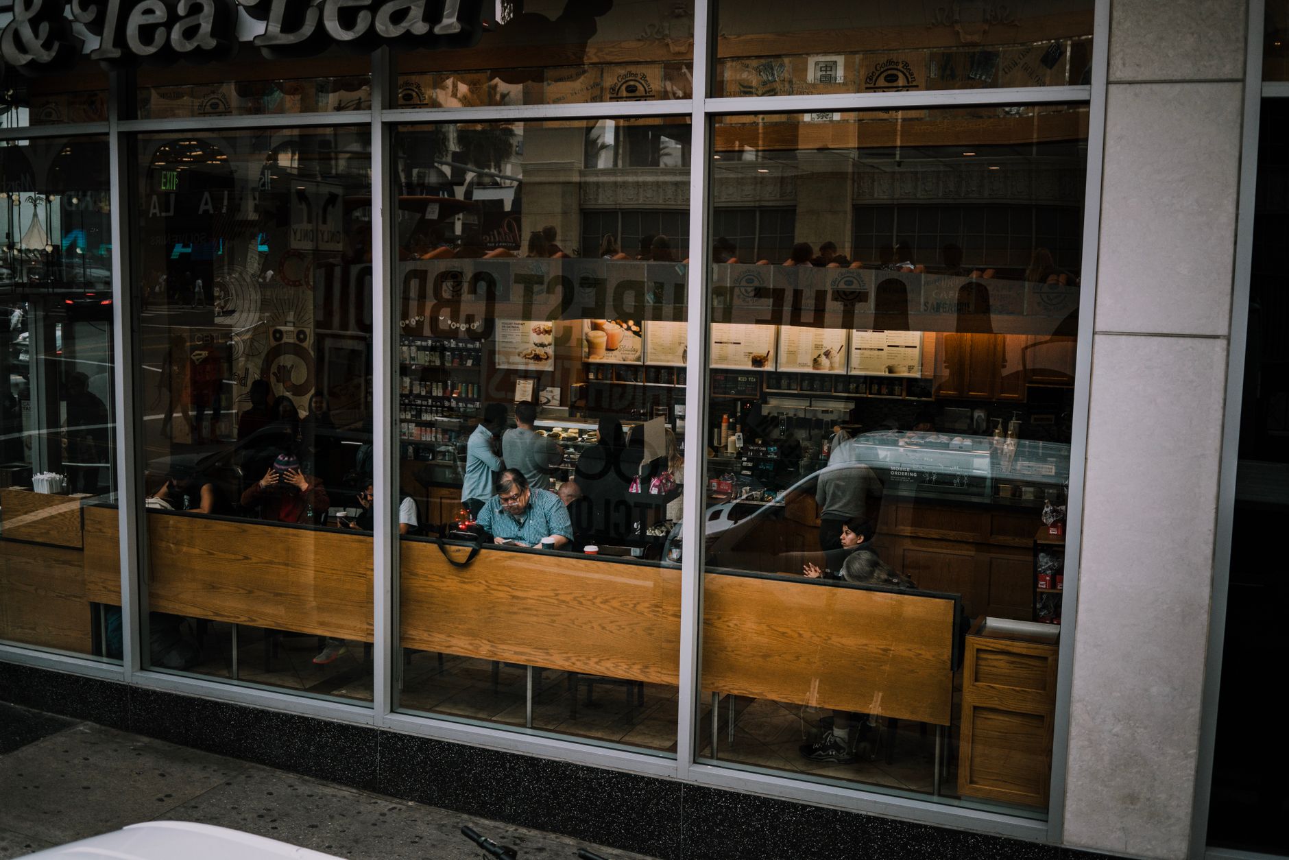 View through window of bustling cafe with customers inside, reflecting city life.