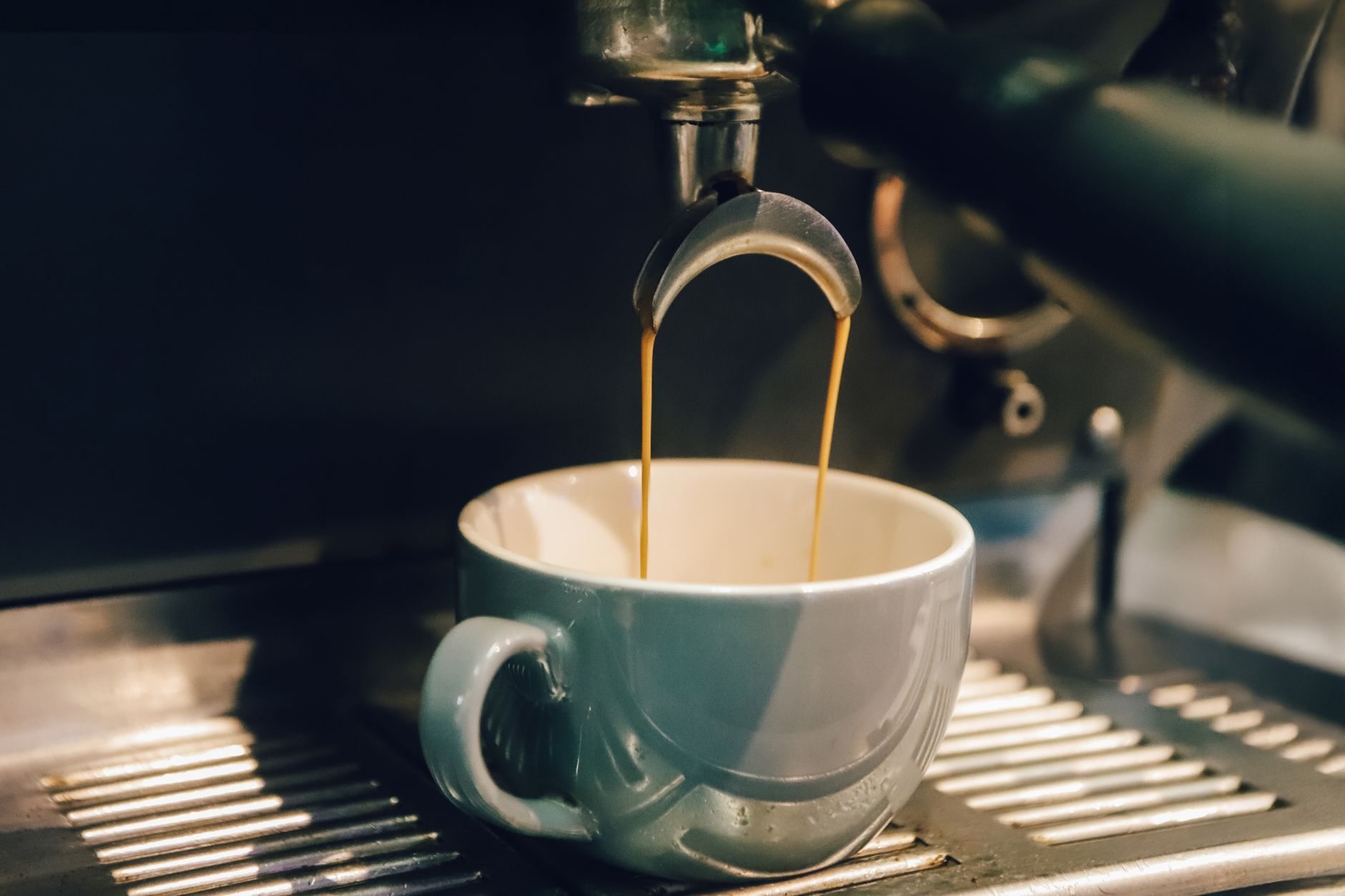 Close-up of espresso machine brewing fresh coffee into a white cup.