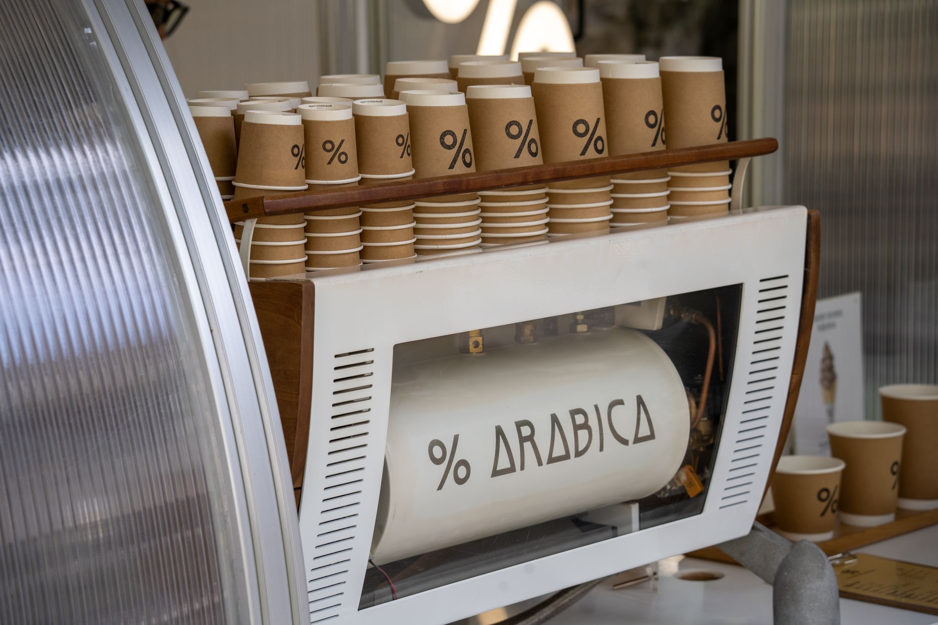 Coffee machine with multiple branded paper cups neatly stacked, showcasing coffee culture.