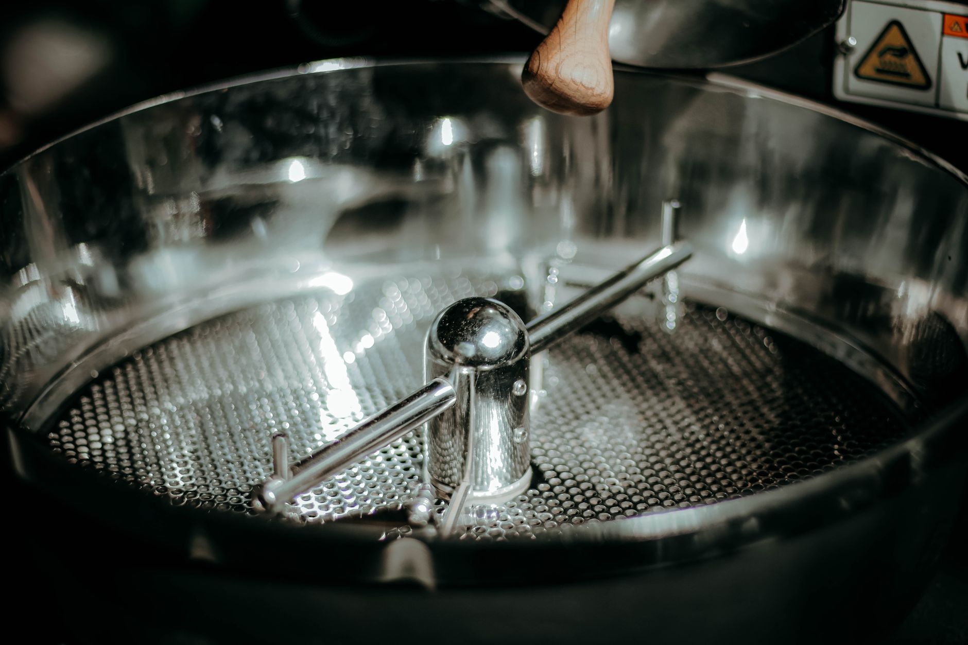Detailed view of a stainless steel coffee roasting machine with textured metal surface.