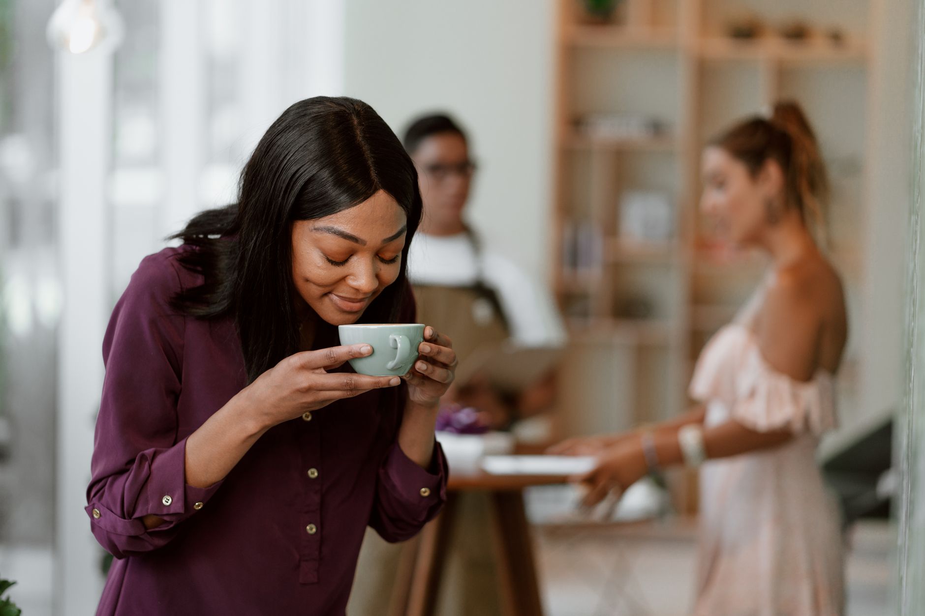 A woman savoring the aroma of coffee in a cozy café setting.