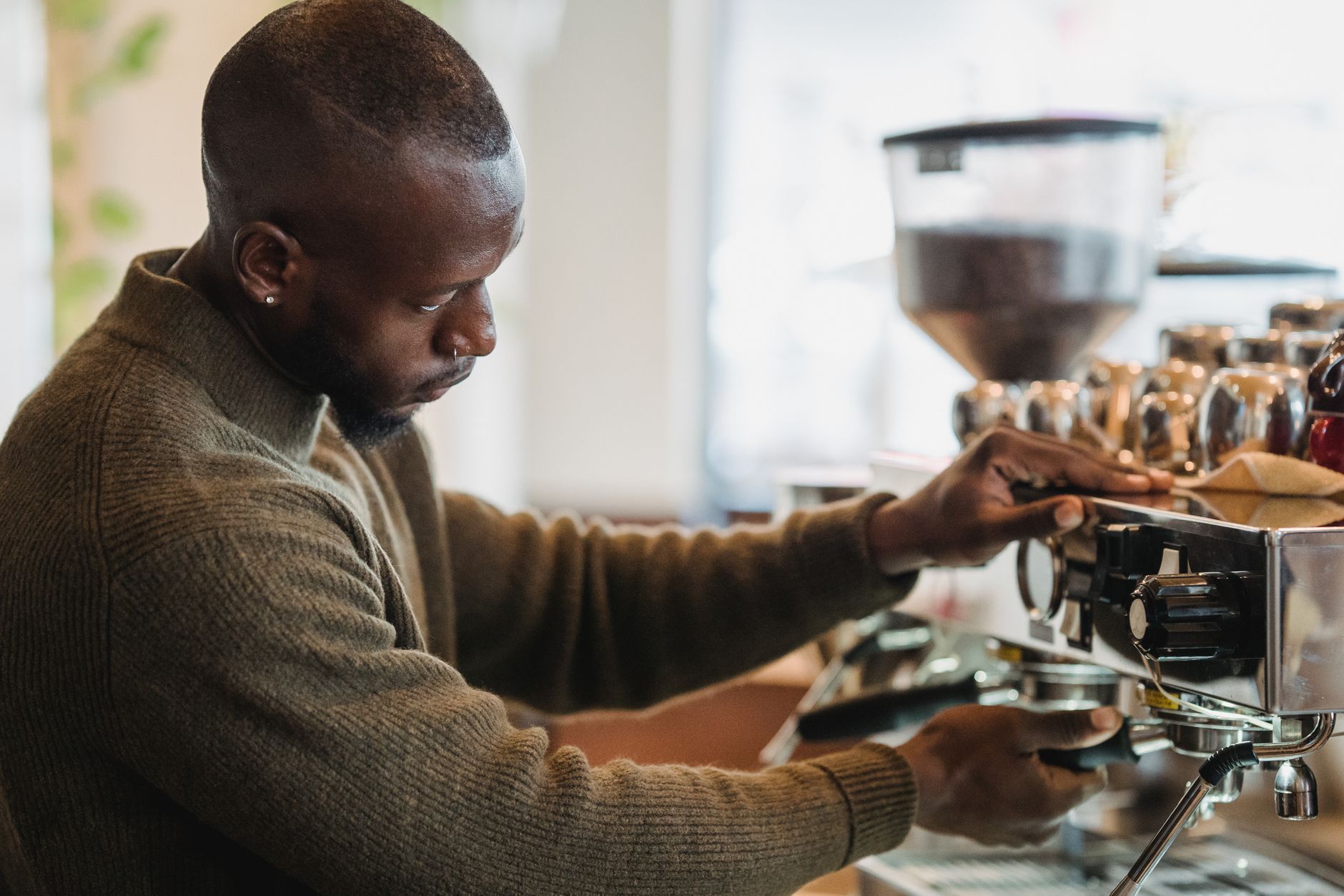 Focused barista brewing espresso with professional espresso machine in cozy cafe setting.