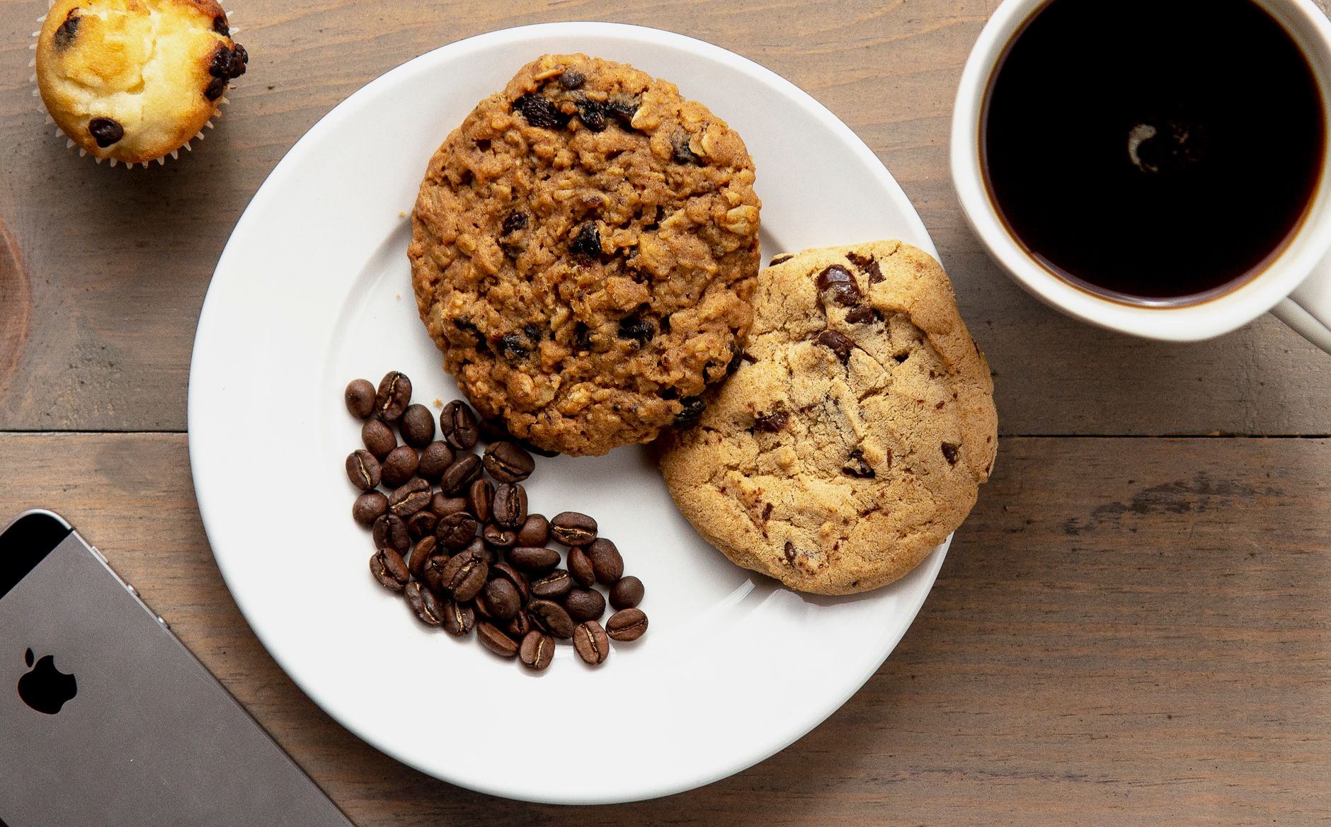 Top view of cookies, coffee, and muffin on a wooden table, perfect for a cozy breakfast scene.