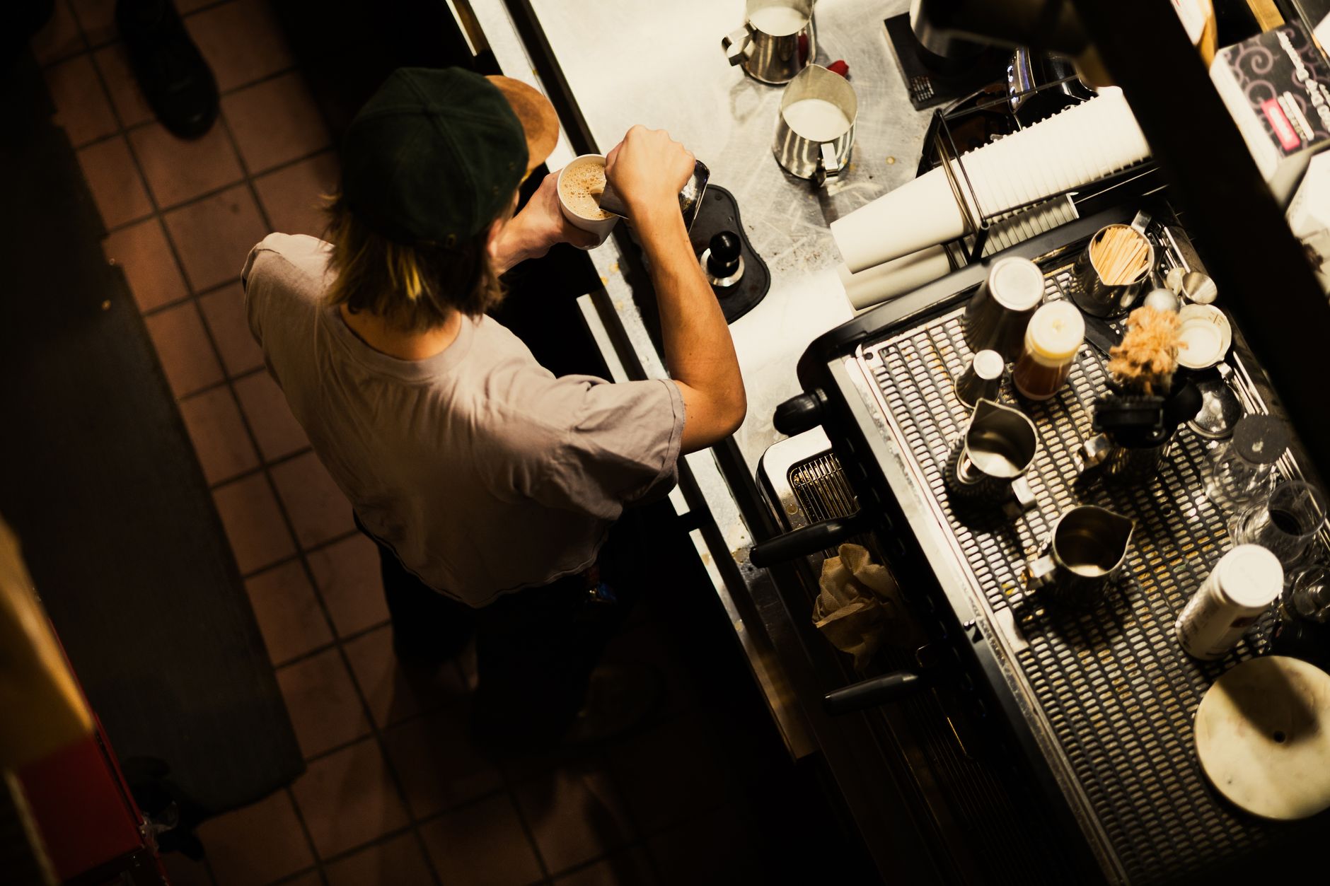Barista preparing coffee, captured from above, highlighting cafe ambiance and artisanal skills.