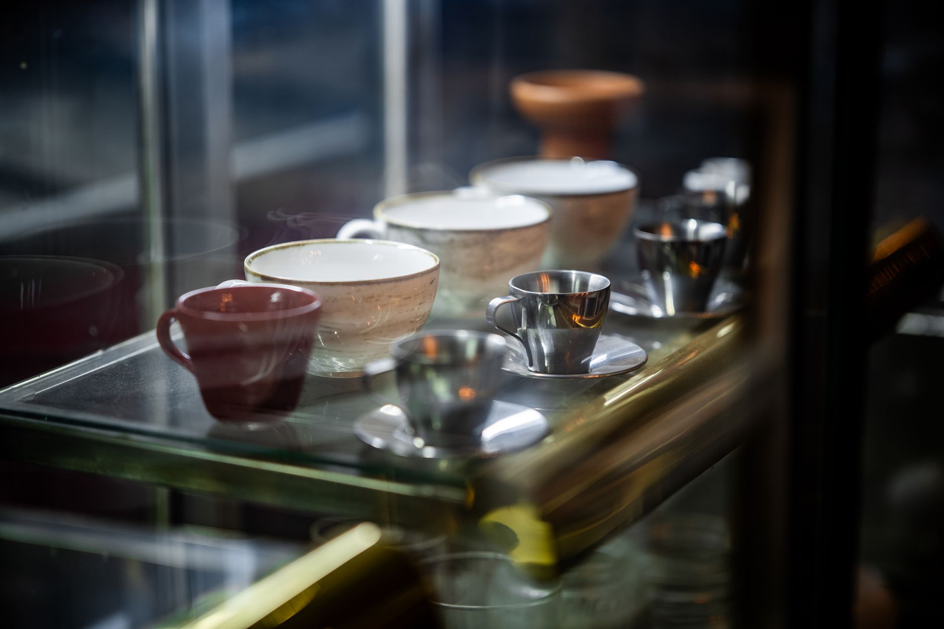 A variety of elegant ceramic and metal cups on display at a café.