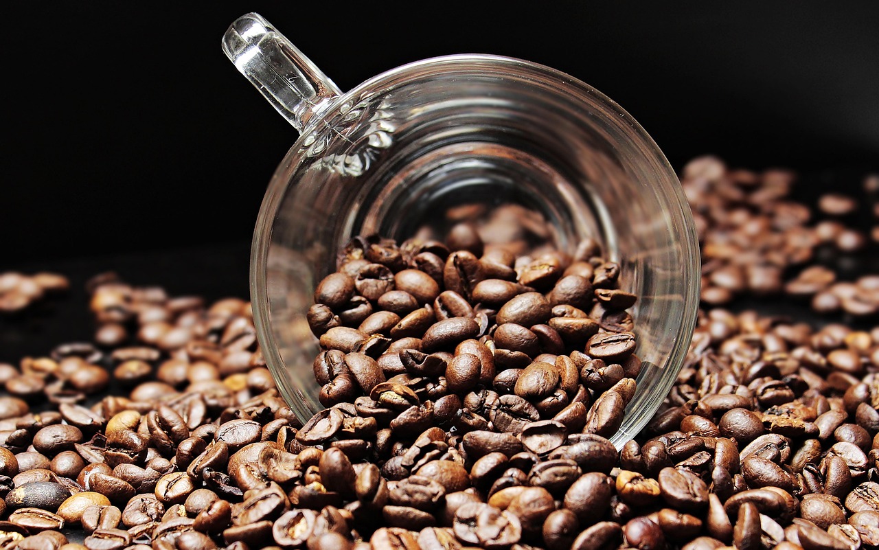 Light roast coffee beans being poured into a white cup