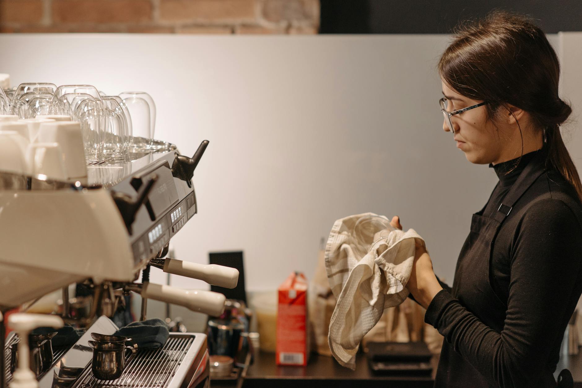Barista inspecting espresso machine group head for cleaning and maintenance