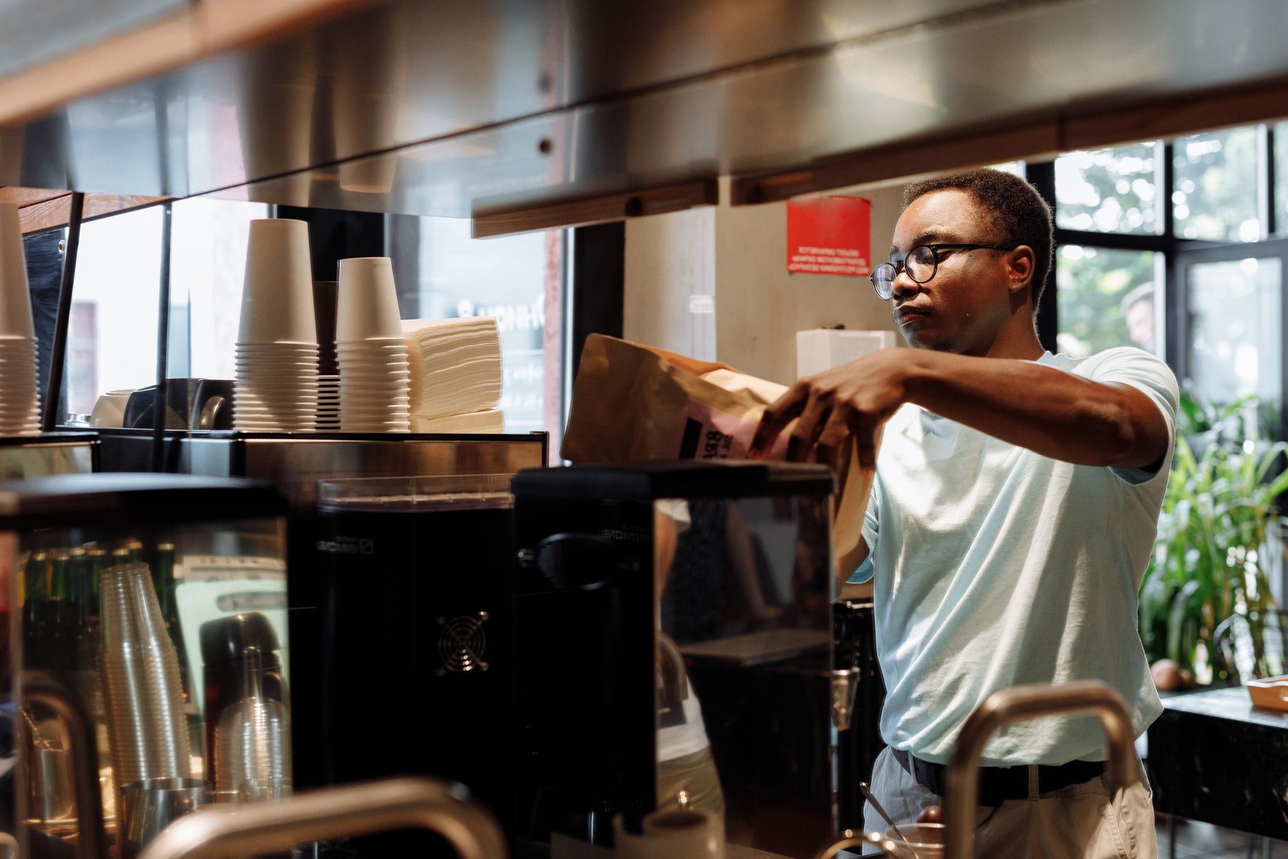 Professional barista operating commercial coffee grinder in restaurant