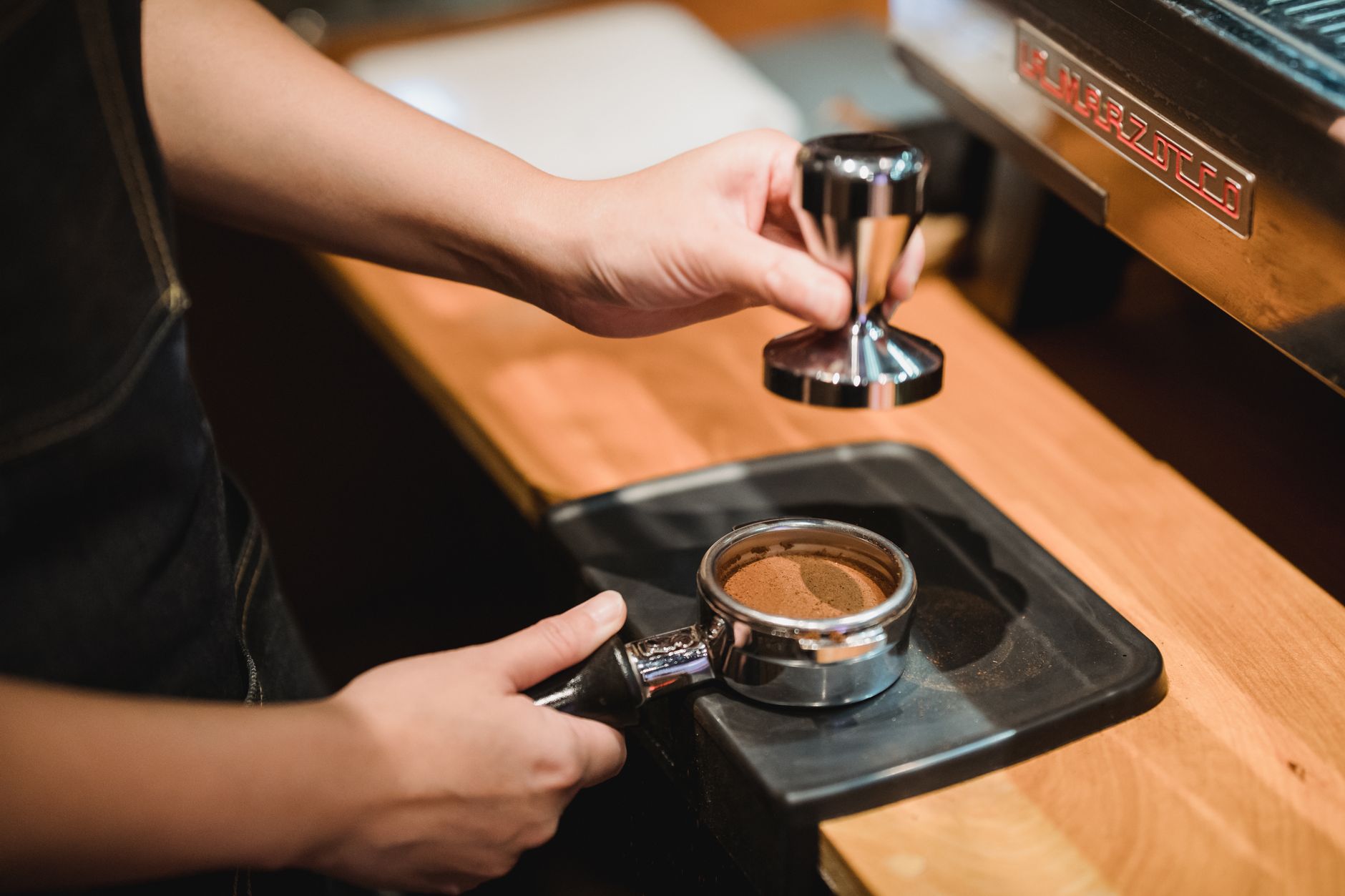 Professional barista demonstrating French press technique during staff training