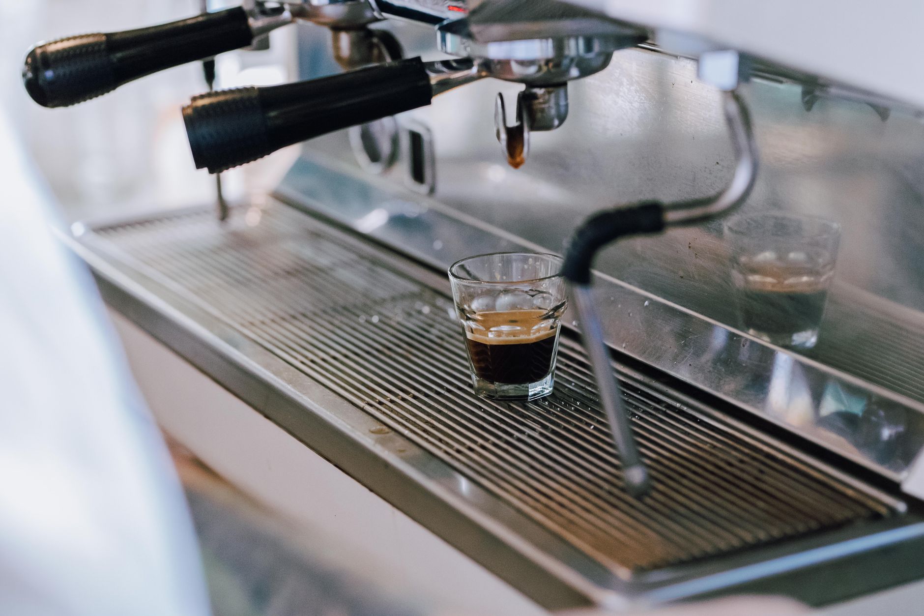 Professional barista frothing milk in stainless steel pitcher