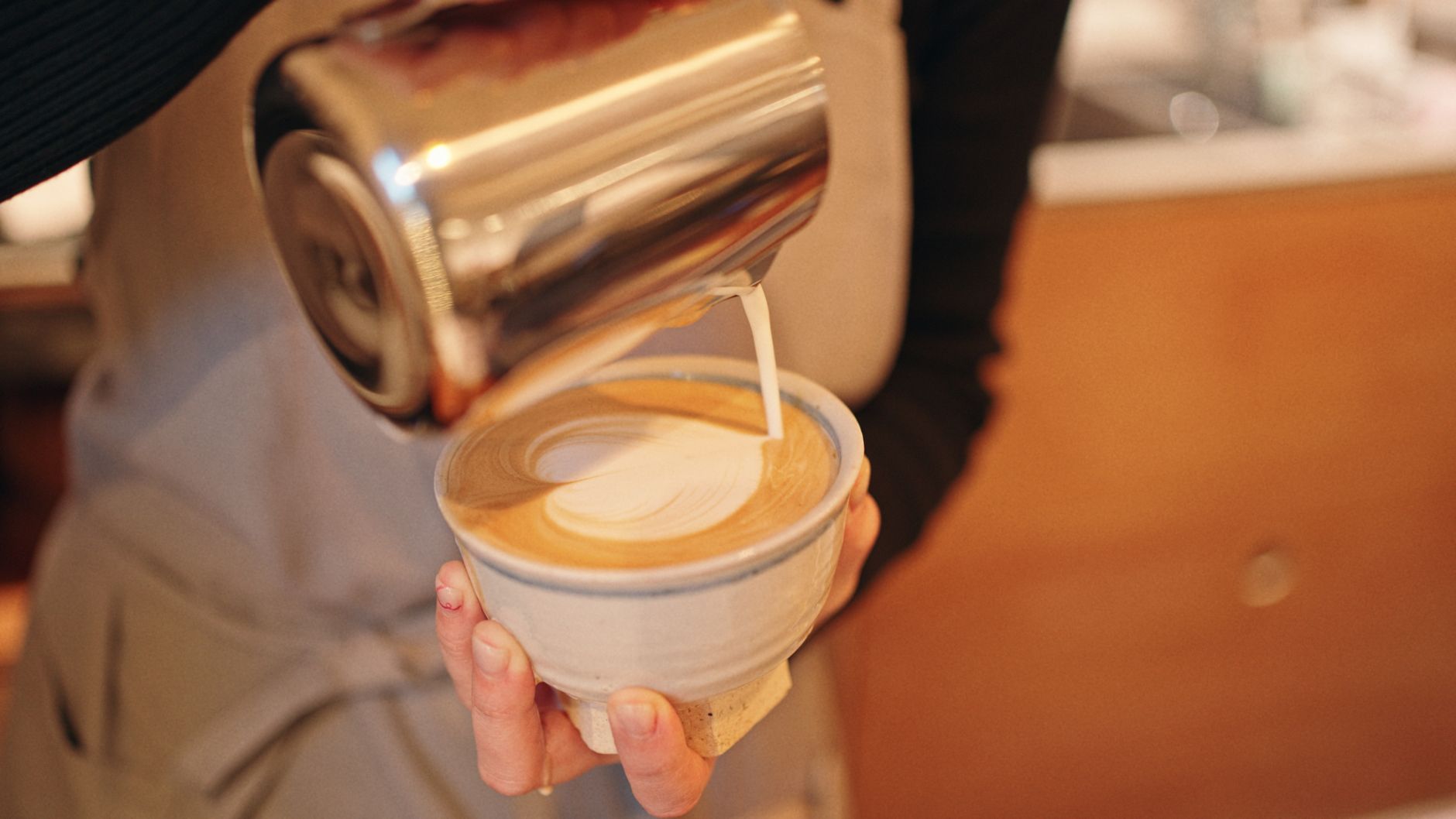 Professional barista pouring perfect rosetta design in a latte