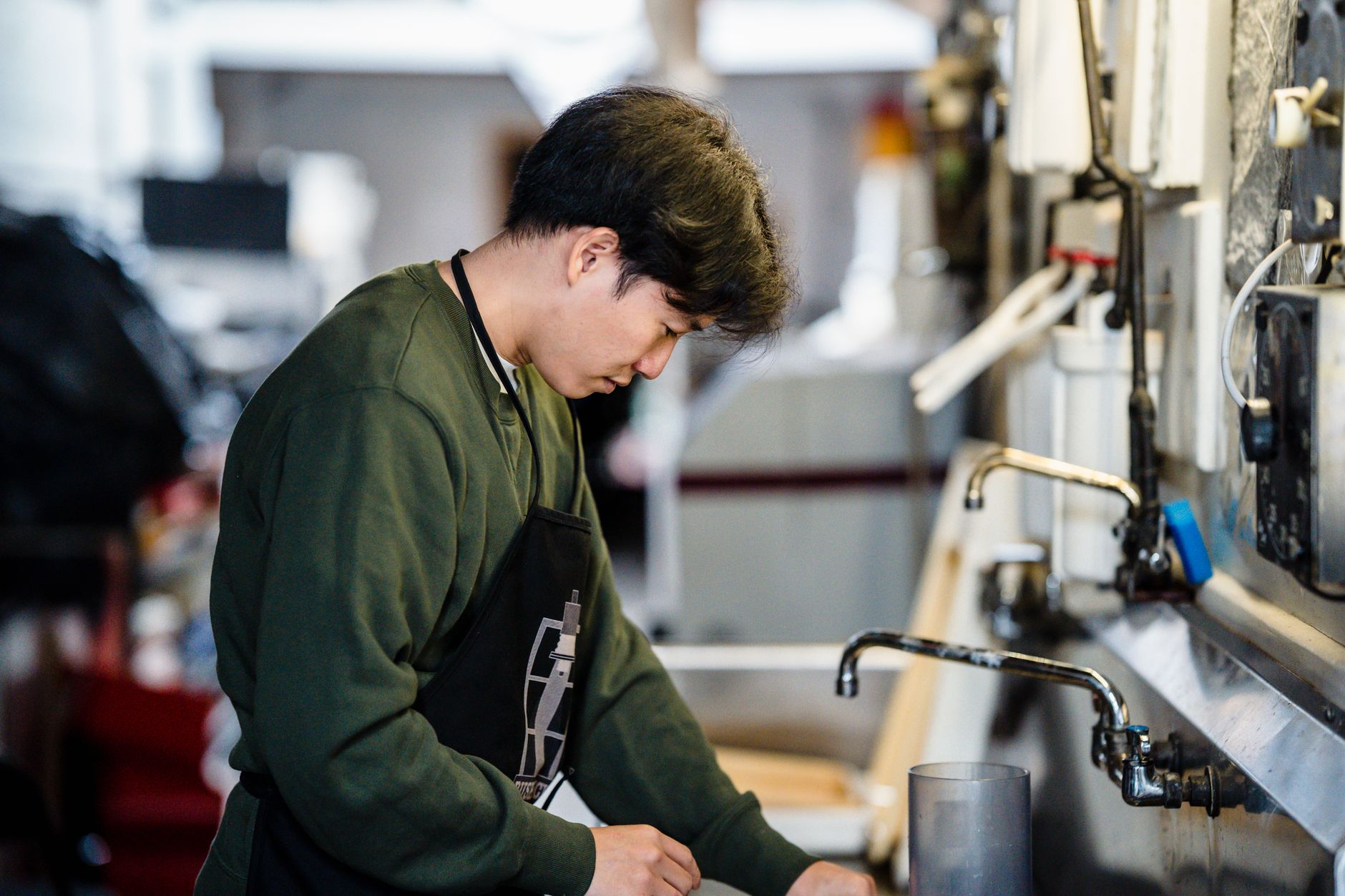 Professional barista cleaning multiple coffee filters at commercial sink station