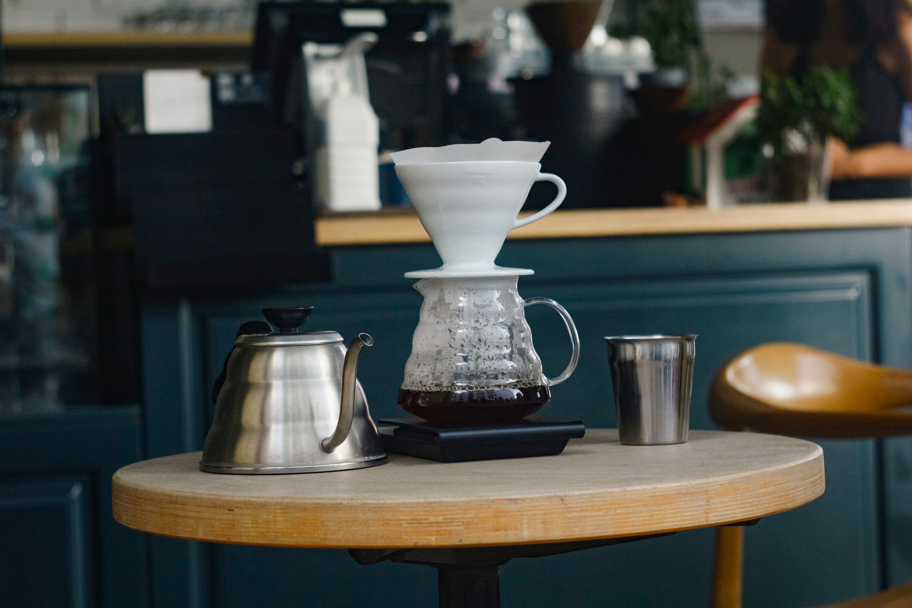 Comparison of stainless steel and glass milk pitchers on a barista counter