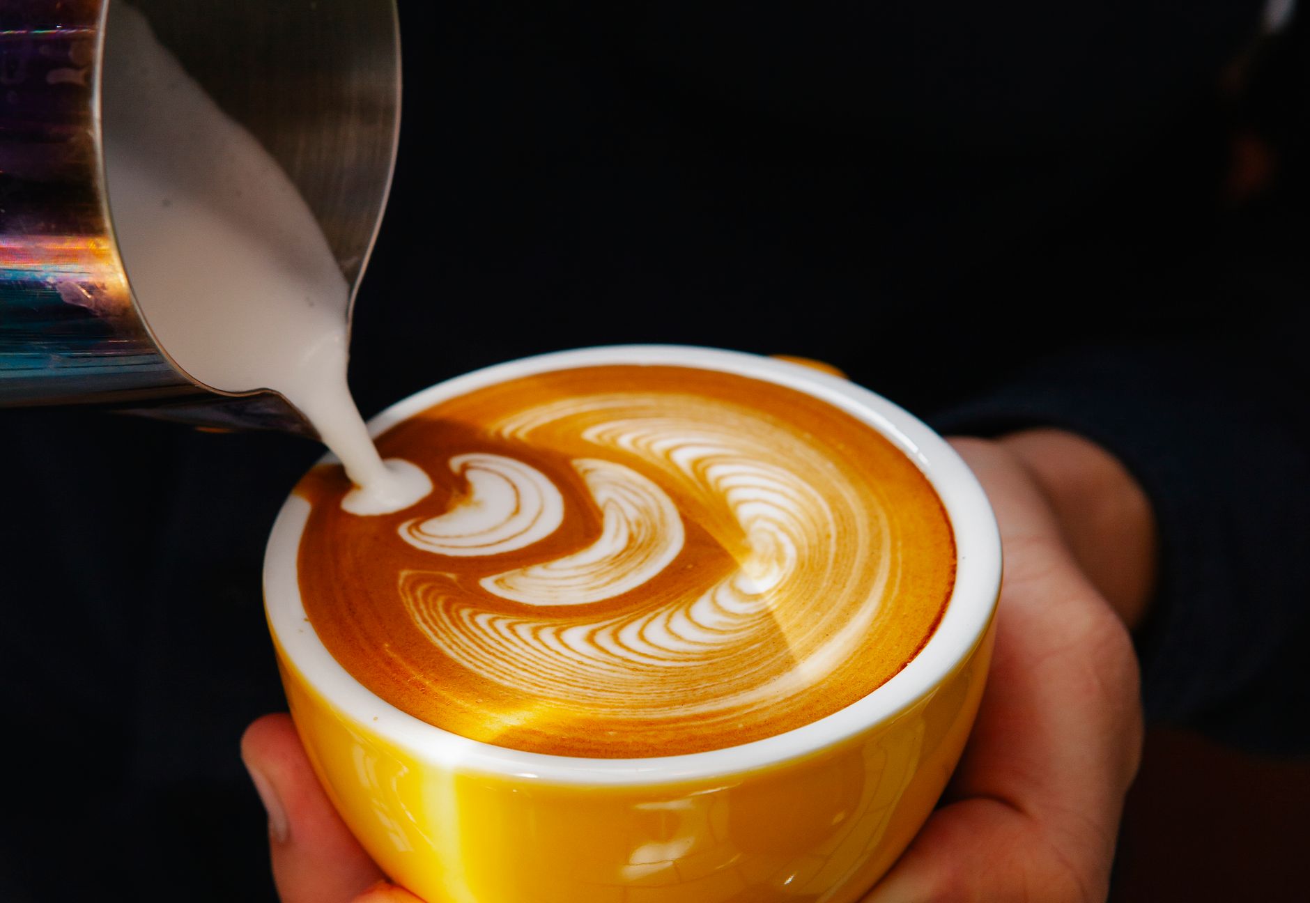 Professional barista creating intricate latte art design