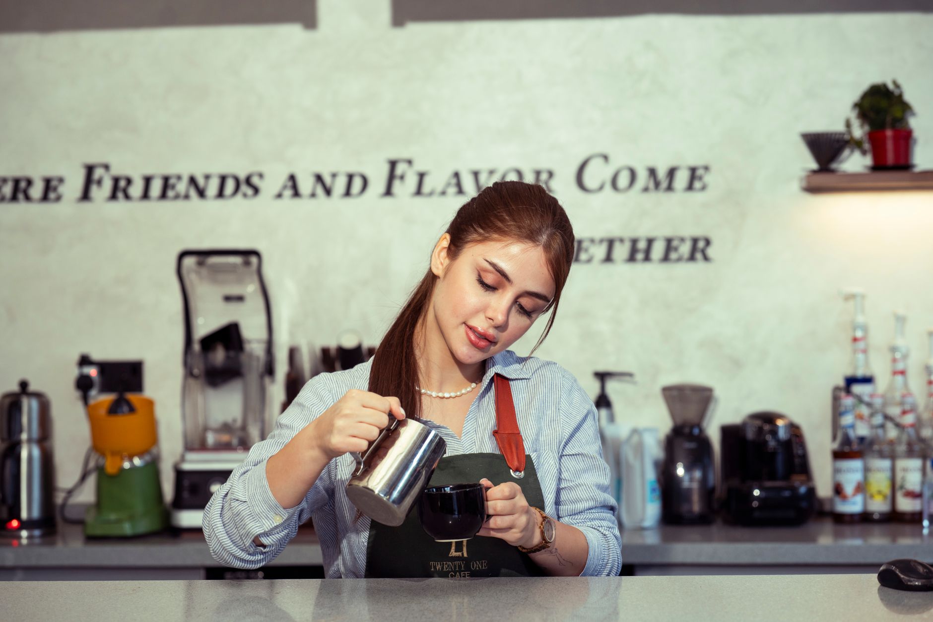Professional barista carefully pouring medium roast coffee from a commercial brewer