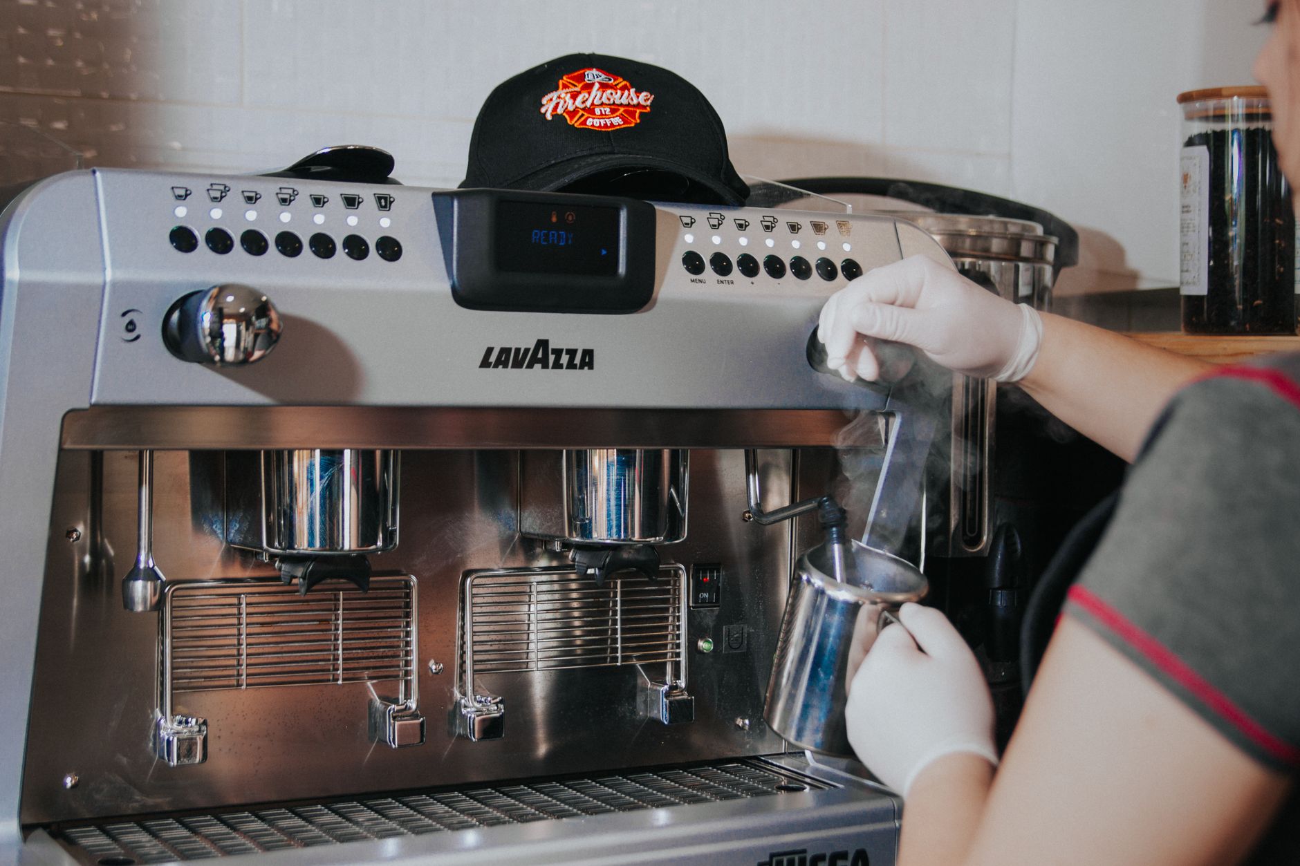 Professional barista using stainless steel frothing wand to create latte art