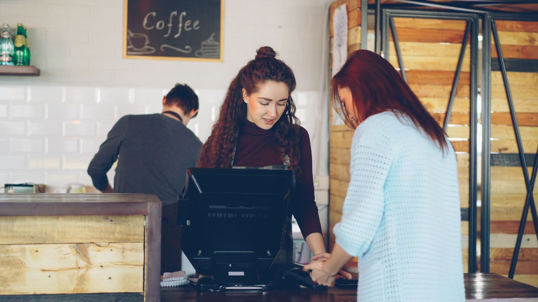 Professional barista preparing milk with an automatic frother in a busy café