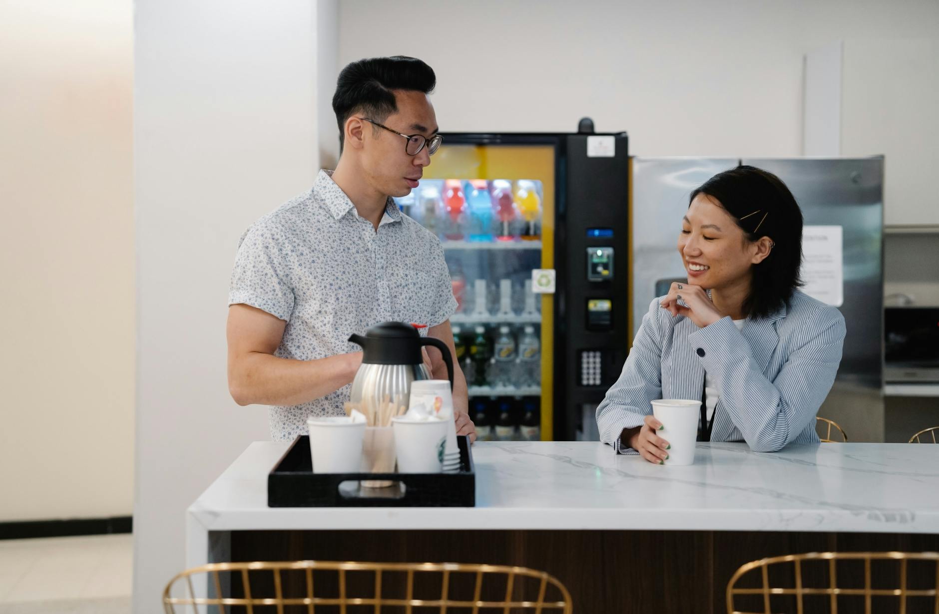 Modern office coffee station with employees brewing drinks